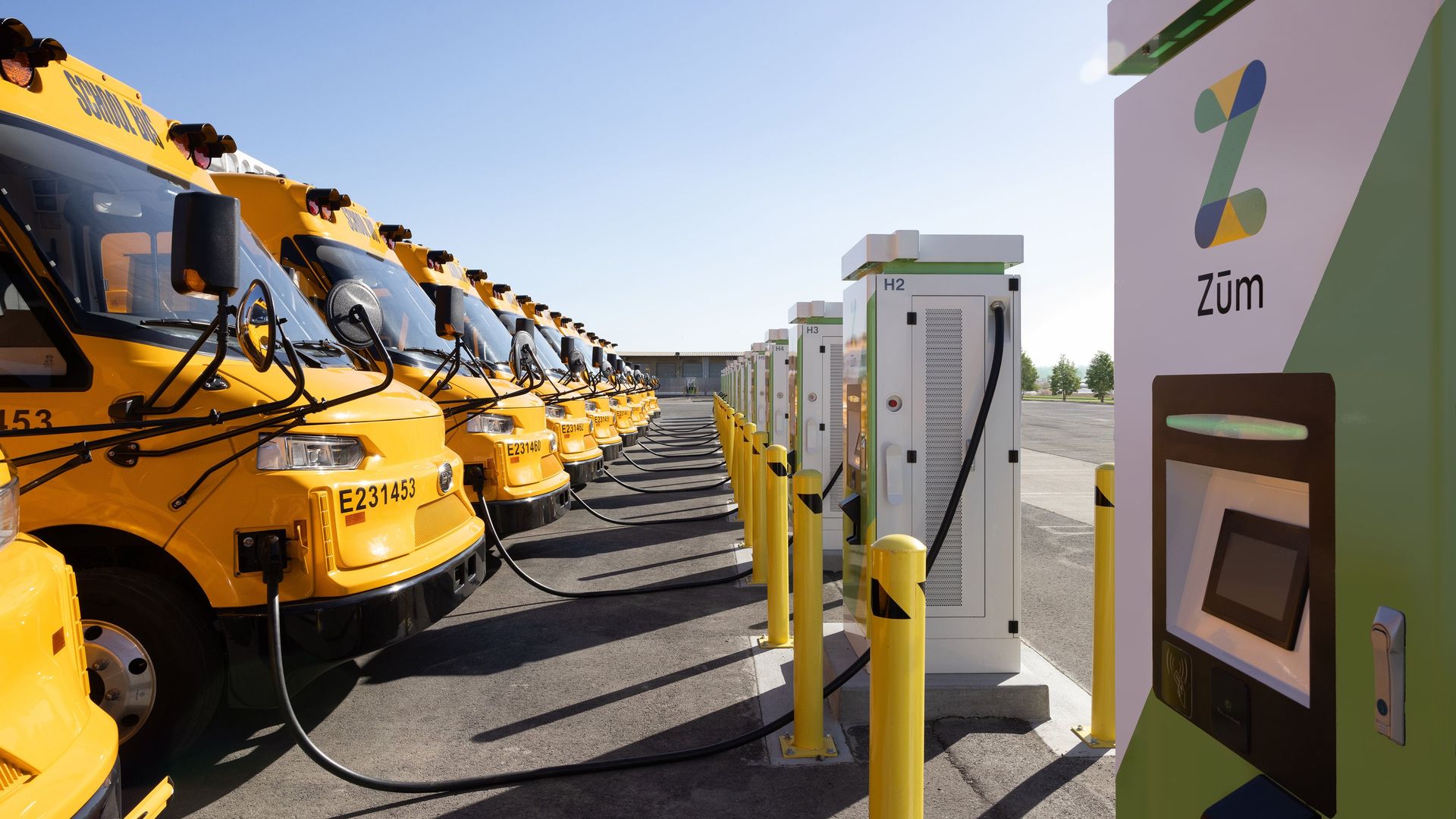 A row of electric school buses plugged into chargers that can send electricity back to the grid in Oakland, Calif.