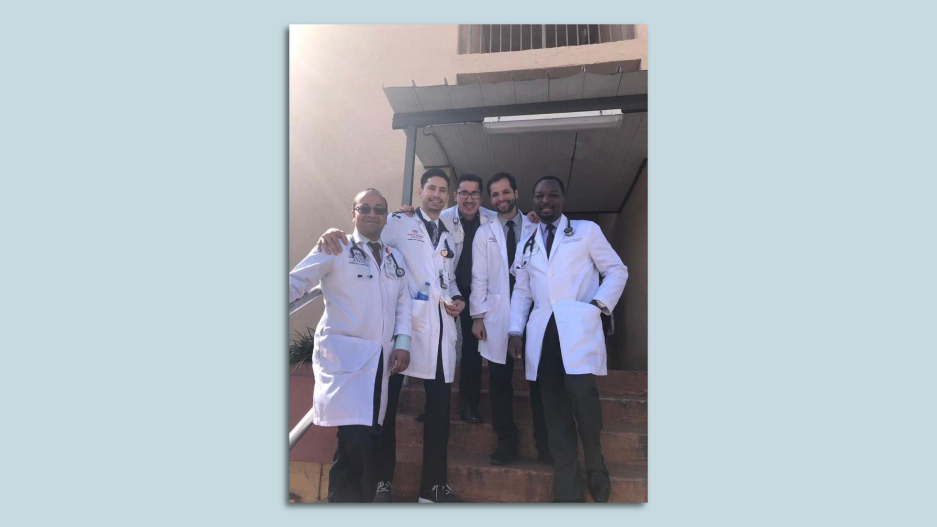A group of doctors in white scrubs stands together 