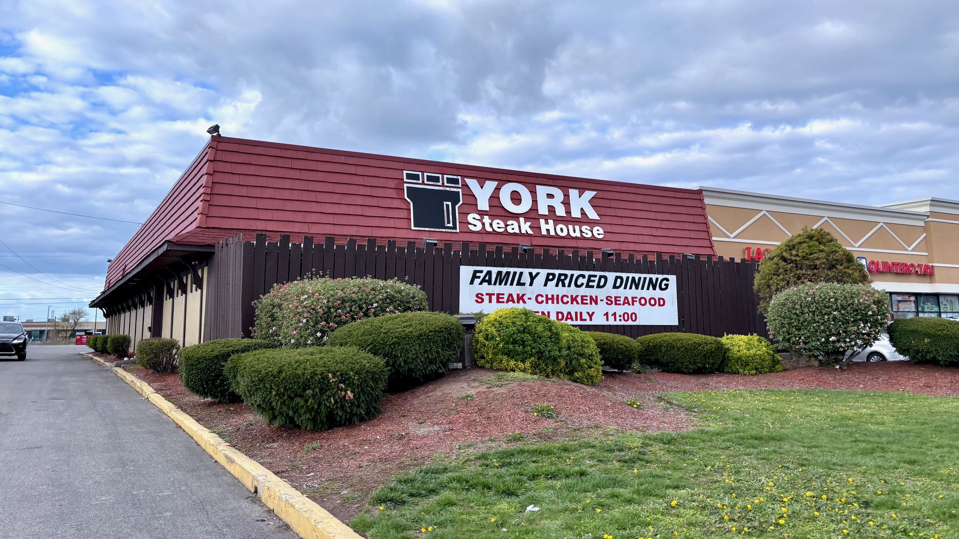 A photo of the York Steak House exterior, with a red roof and a sign that says "family priced dining - steak, chicken, seafood"