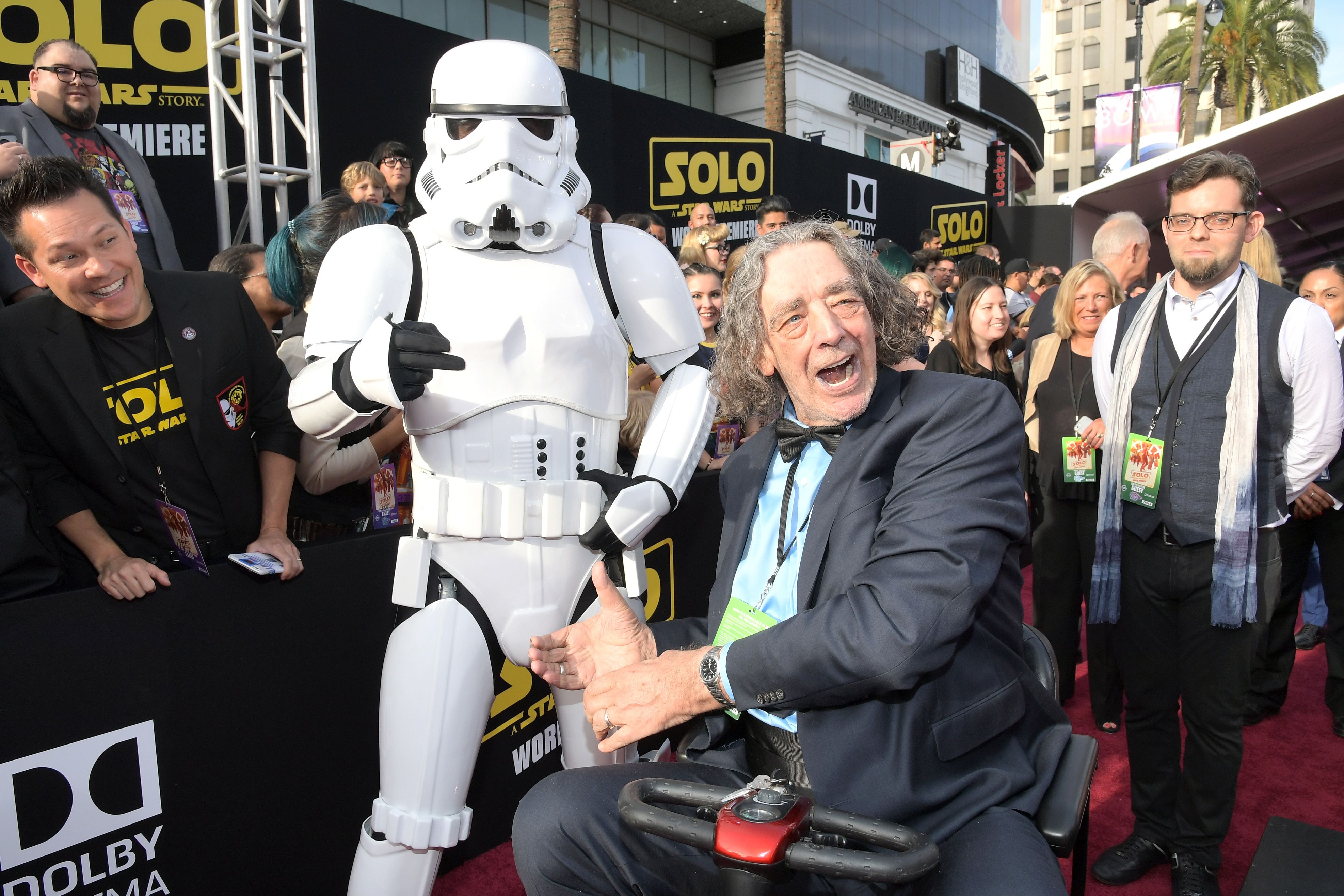 In this image, Peter Mayhew sits in an electric wheelchair on the red carpet.