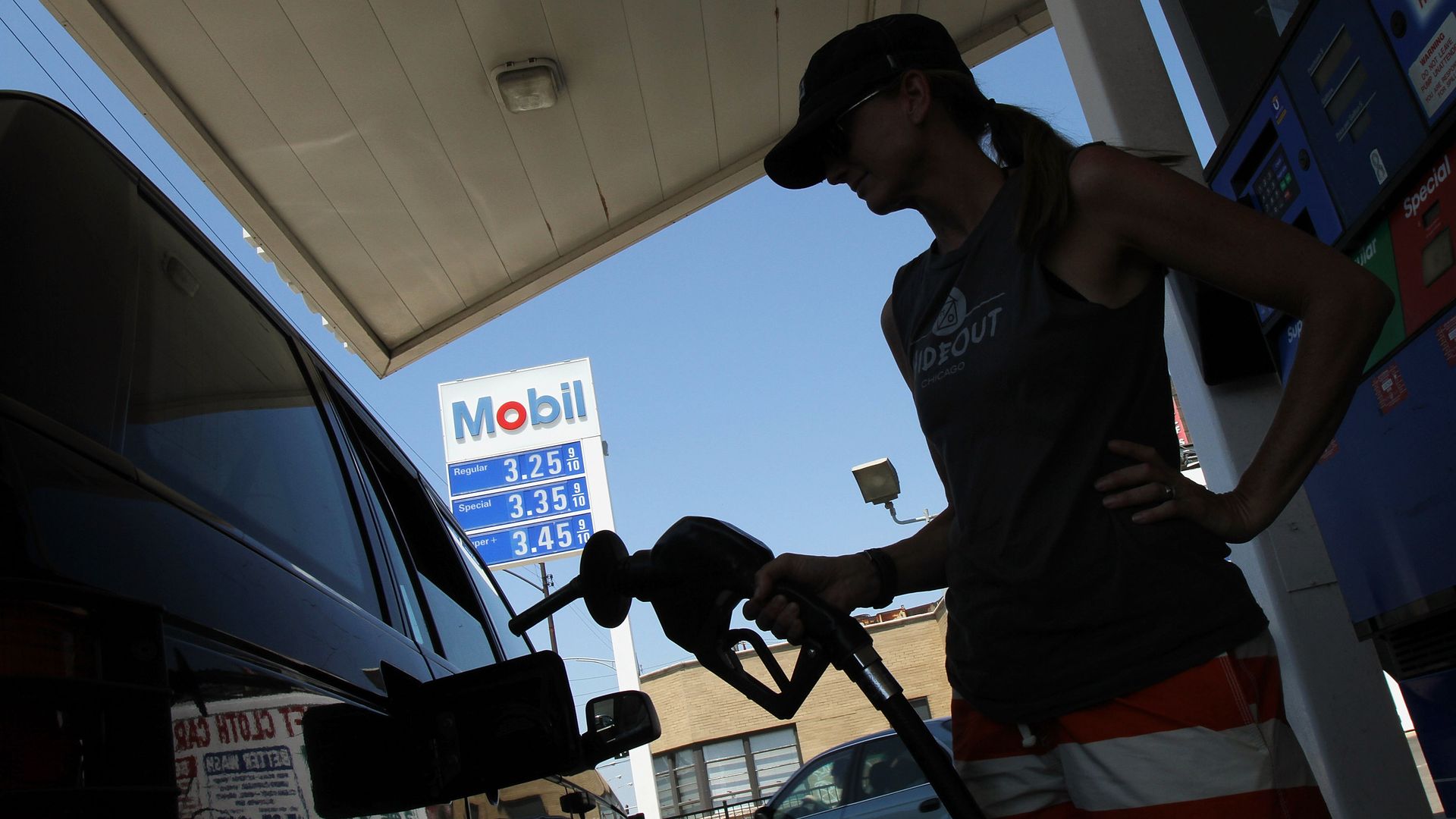 A woman filling up her car at an Exxon station.