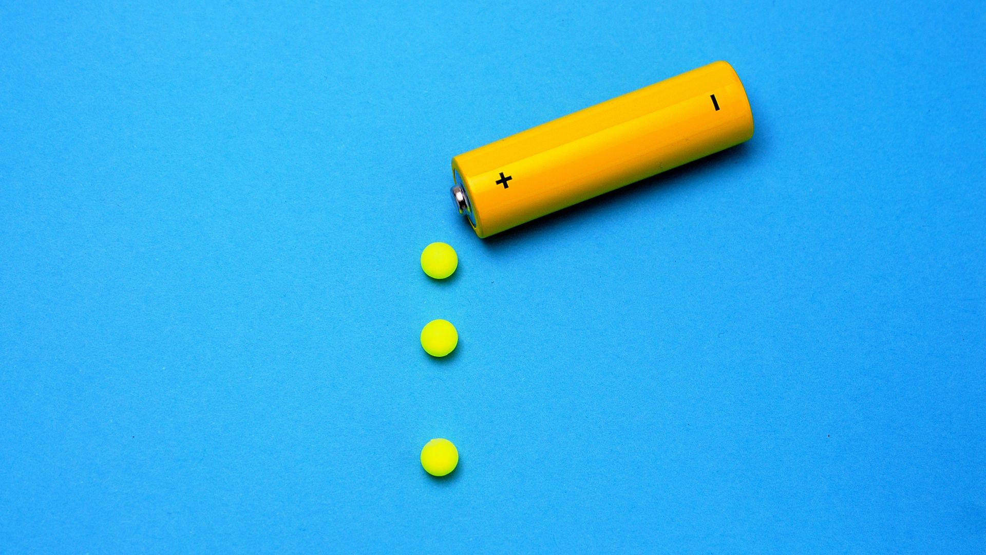 In this image, a yellow battery drips yellow circles on top of a blue background.
