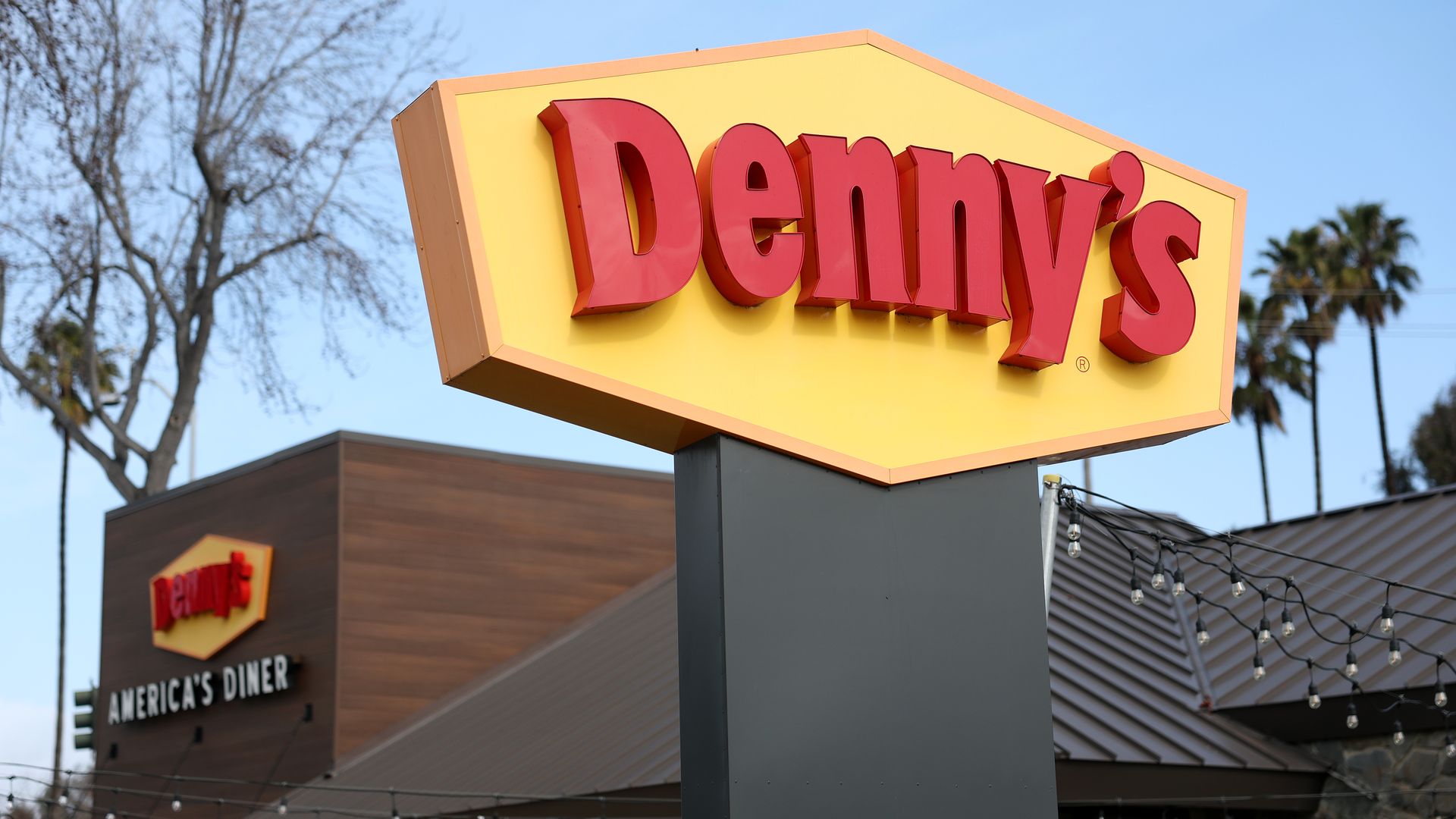 A view of the exterior of a Denny's restaurant along with its yellow sign with the letters in red