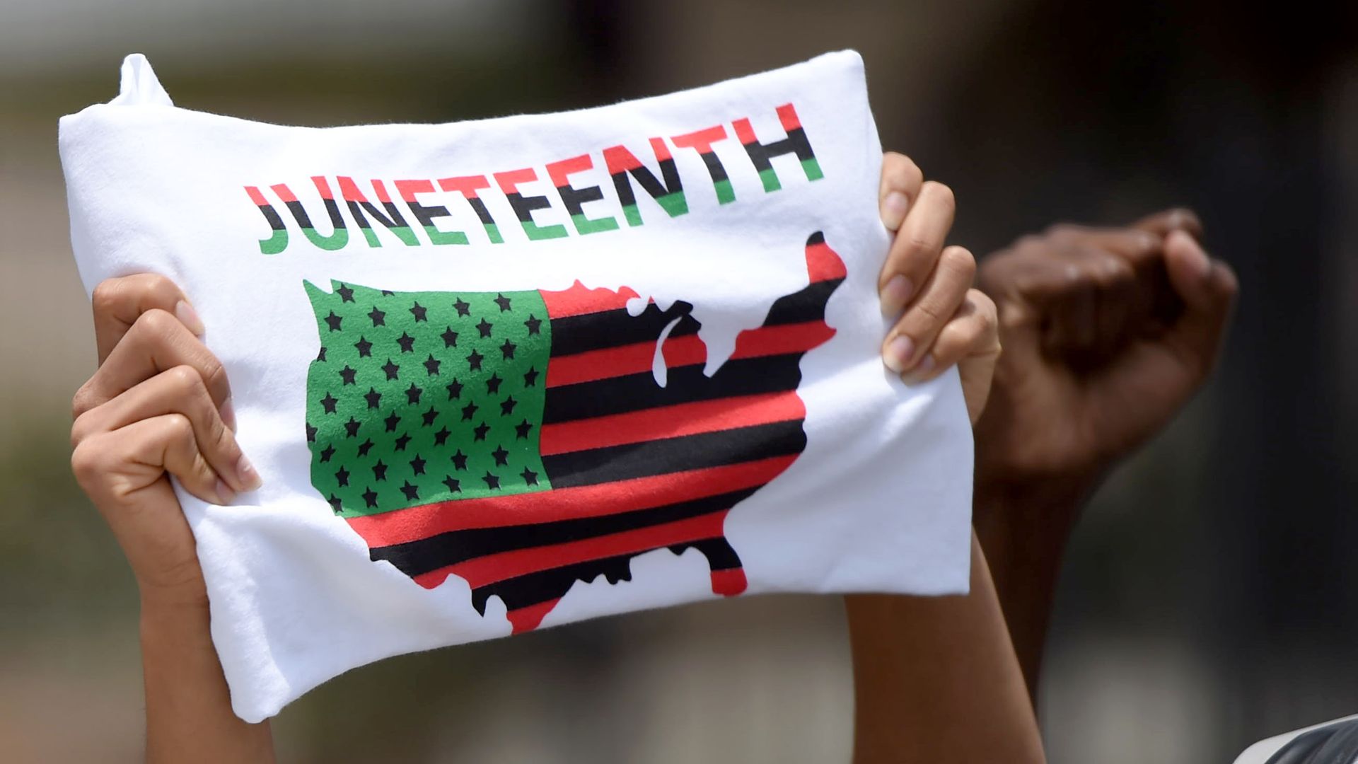 A woman holds up a sign that says Juneteenth with a map of the U.S.