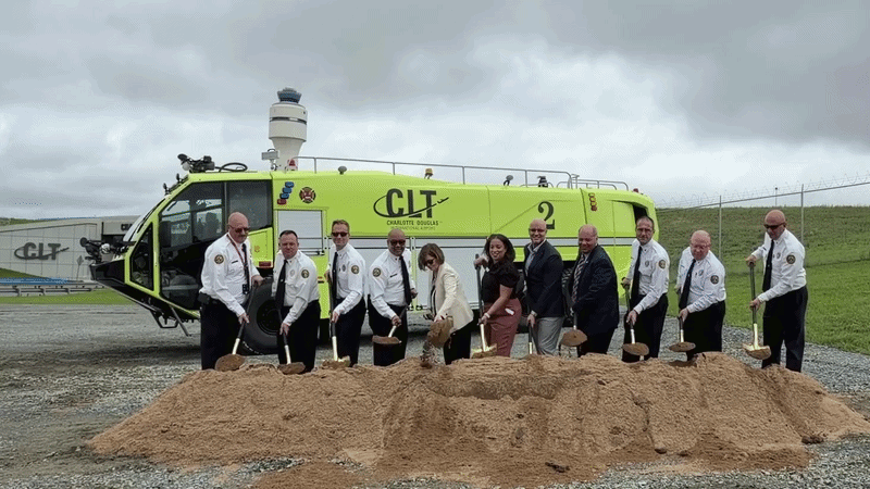 Firefighters and other city leaders toss dirt with shovels in a ceremonial groundbreaking for Firehouse 47 at CLT. 