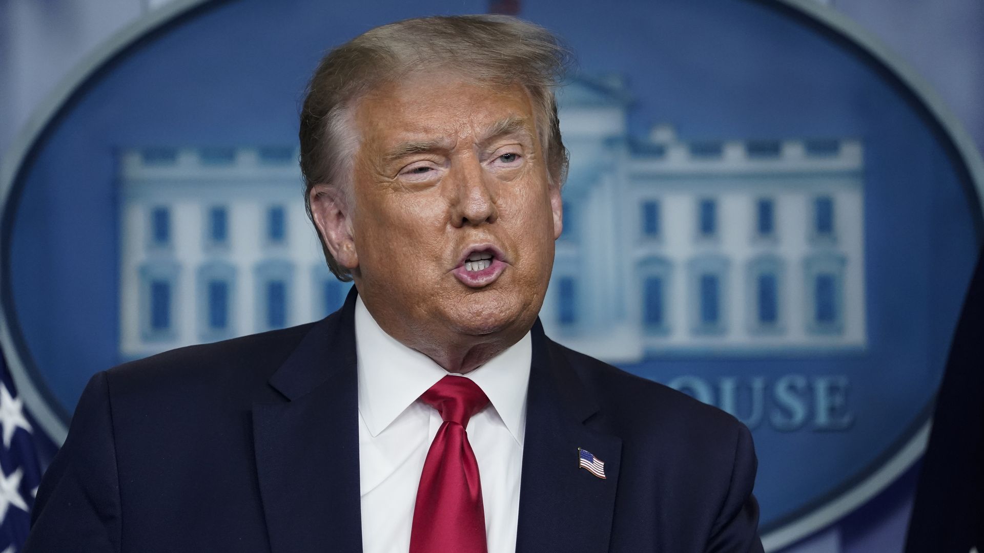 Trump in a suit at a press briefing 