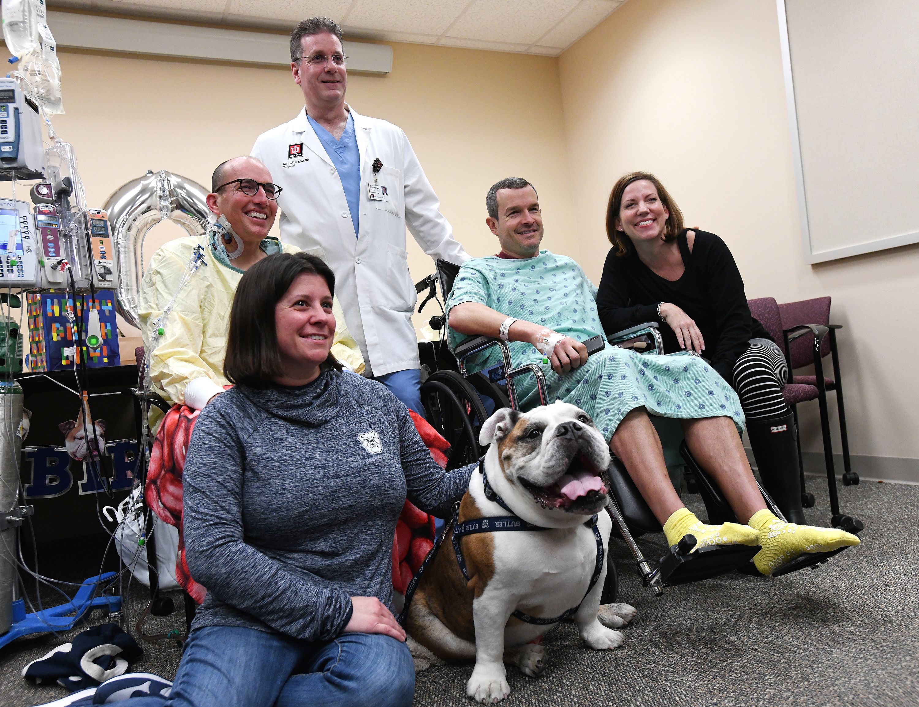 Two men in wheelchairs with their wives, a doctor and a bulldog