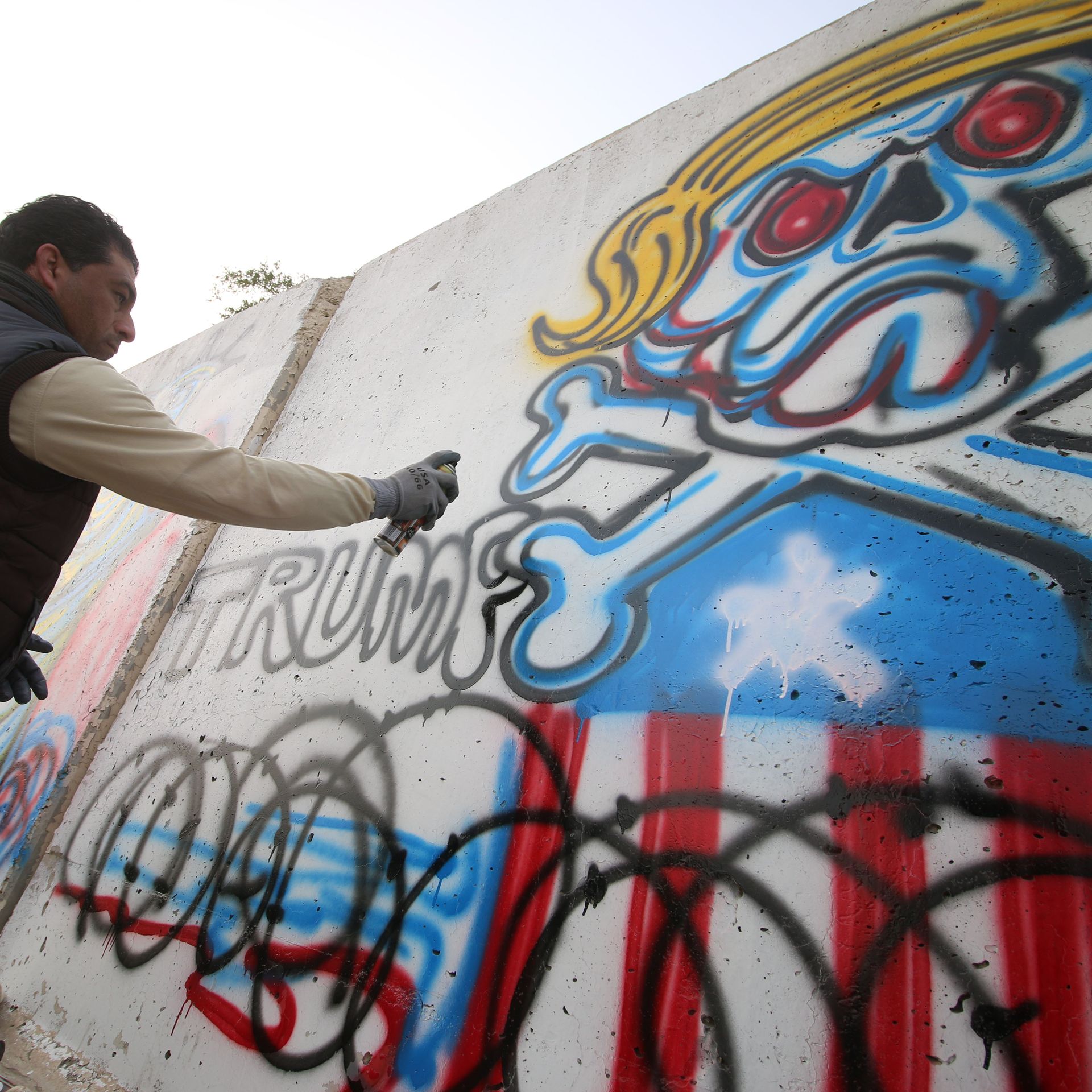 An Iraqi graffiti artist sprays a cement wall with anti-US President Donald Trump slogans in the southern Iraqi city of Basra on February 2, 2017.