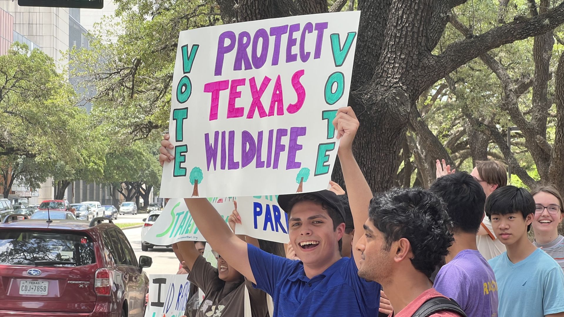 A person holds up a sign that reads "Protect Texas wildlife" and "vote" 
