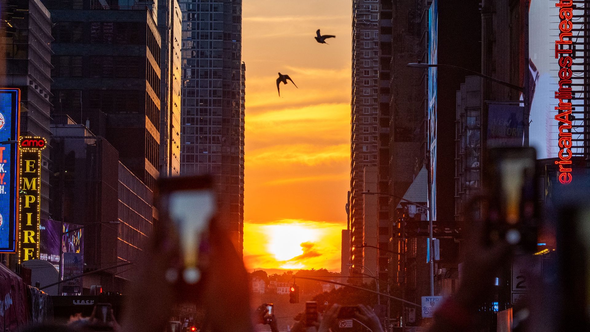 New Yorkers watch the sun set in between Manhattan skyscrapers