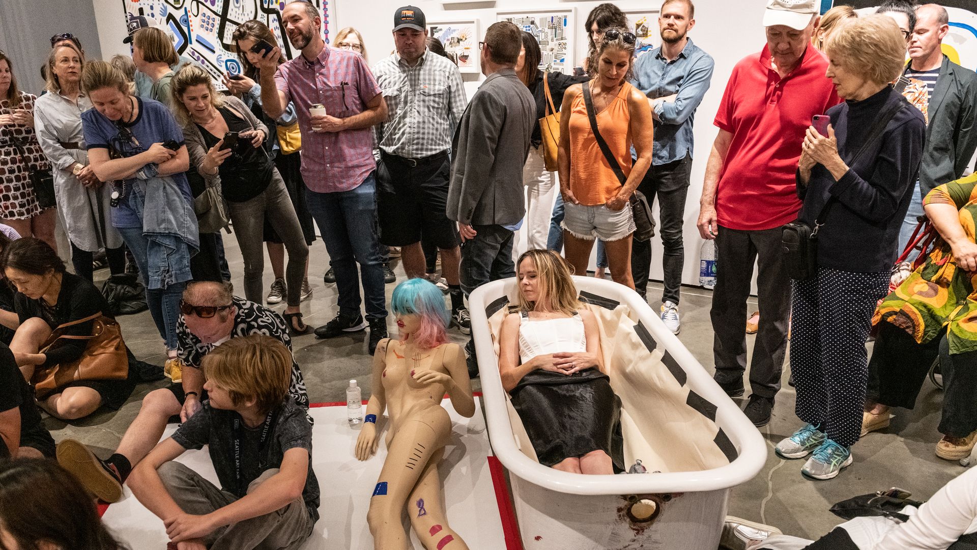 An artist lies in a bathtub at a performance art exhibit. 