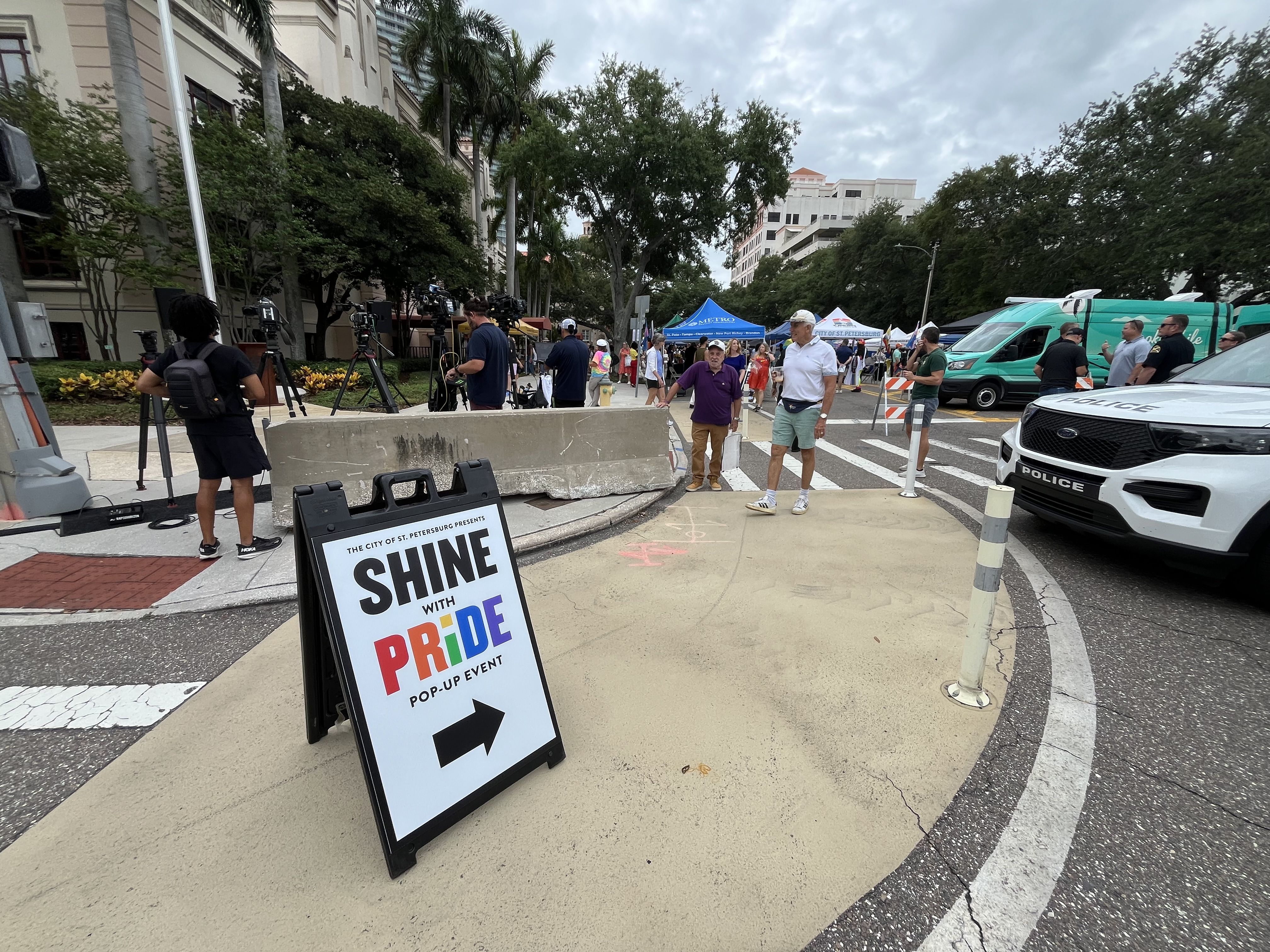 A sign reads "Shine with Pride pop-up event" with an arrow pointing toward a block party. 