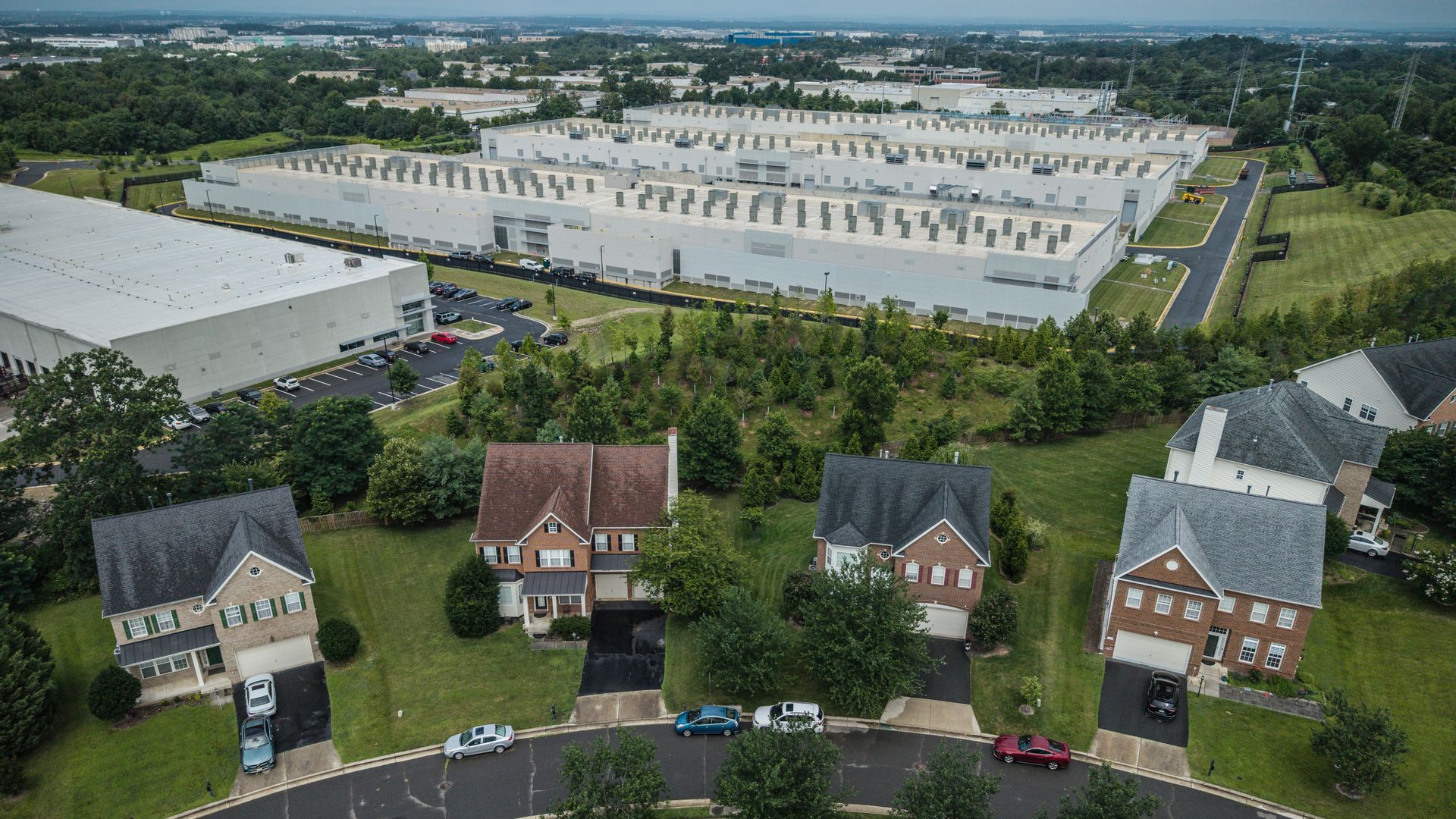An image of houses, with a large data center behind them.