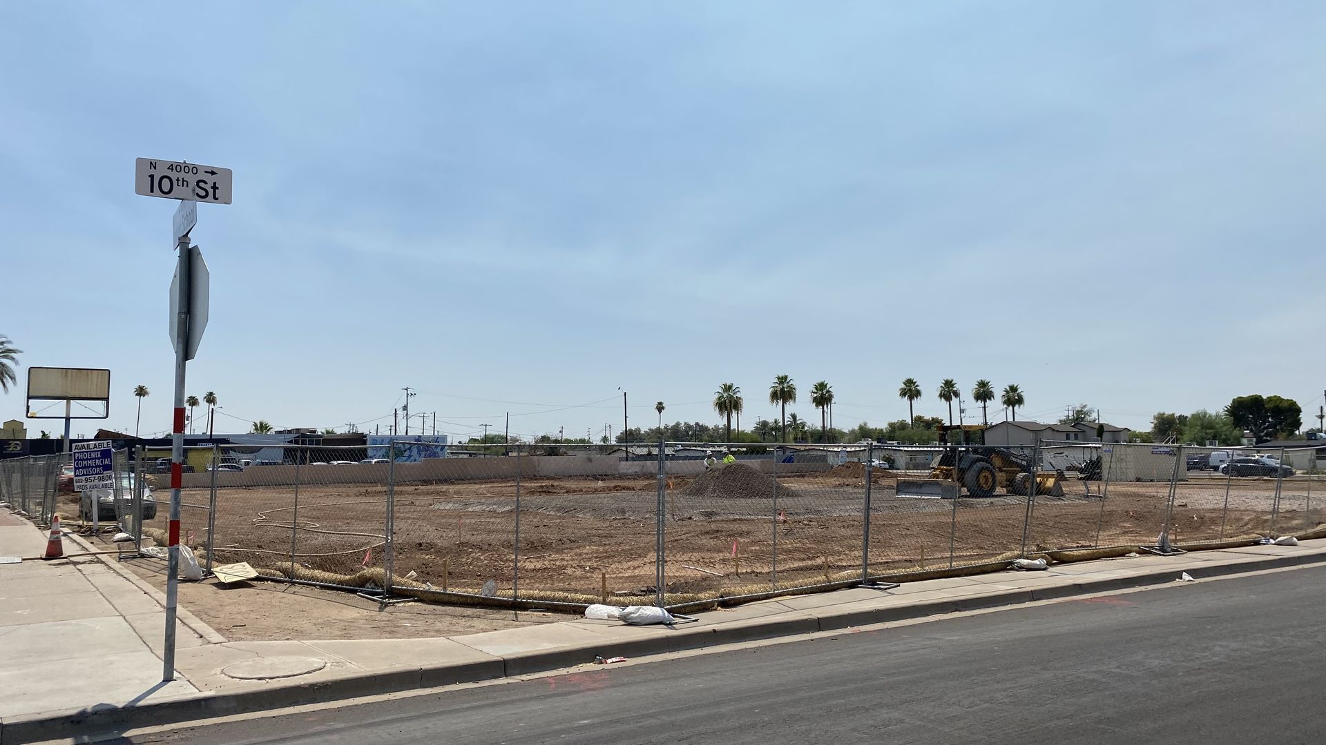A dirt lot with a bulldozer surrounded by a chain link fence.