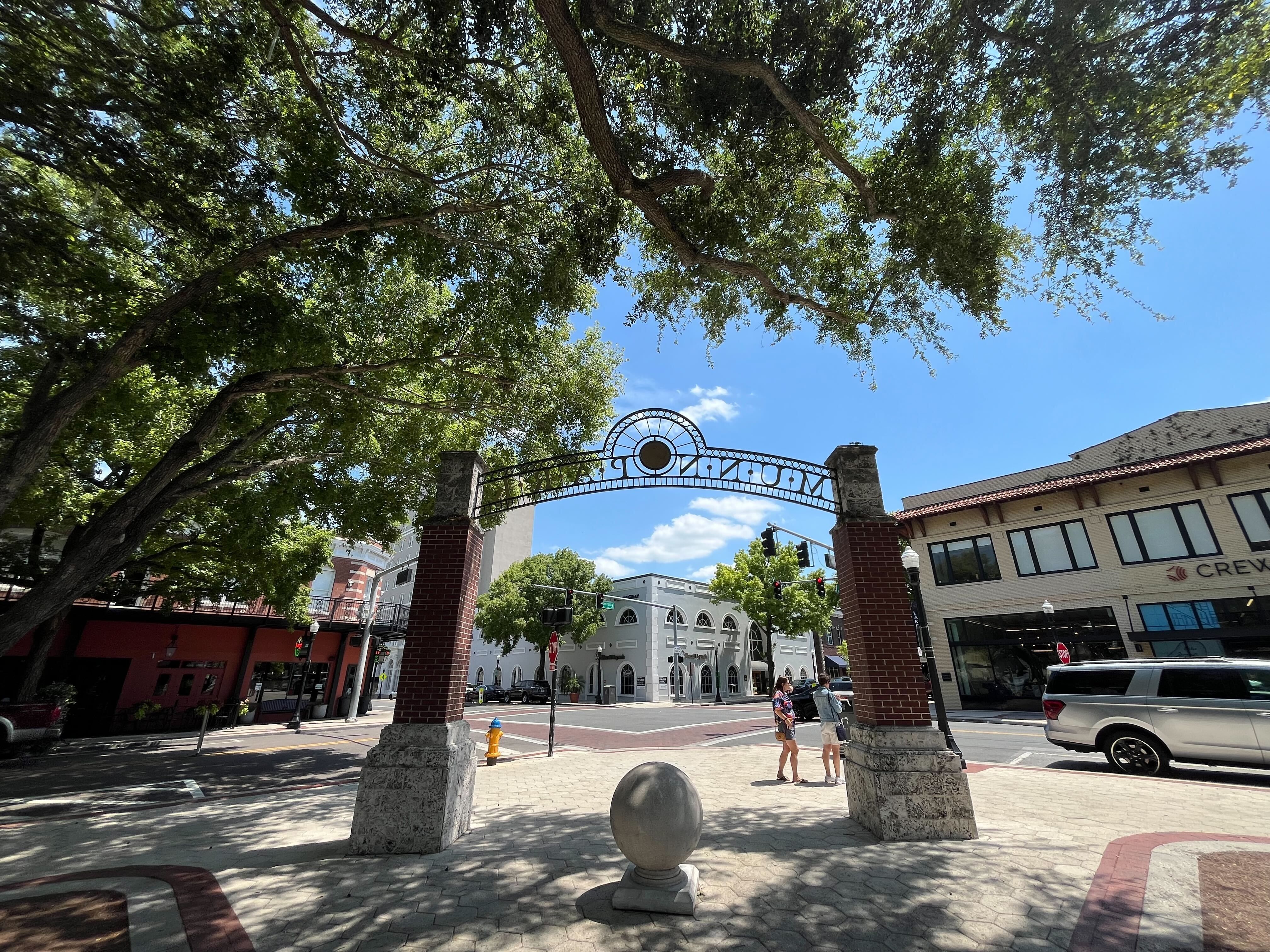 A view of a downtown block through the arches of a park entrance.