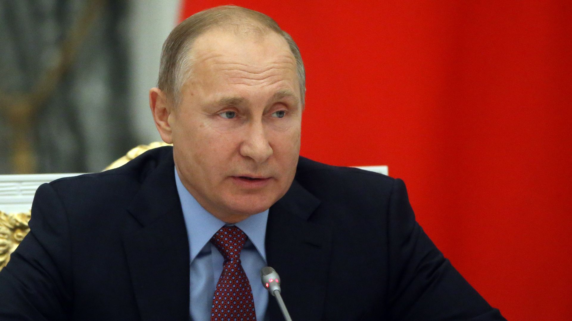 Vladimir Putin seated at microphone during meeting