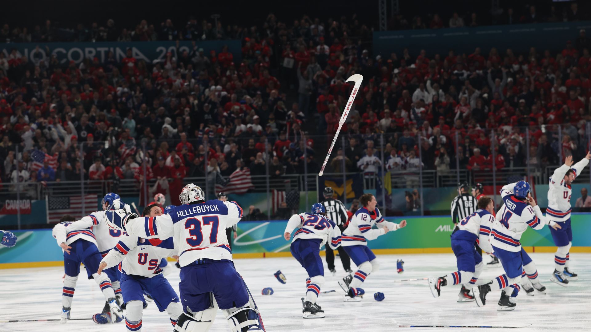Goalie Connor Hellebuyck throws his stick in the air as the U.S. defeats Canada 2-1 in overtime to claim the gold medal Sunday at the Winter Olympics in Milan.