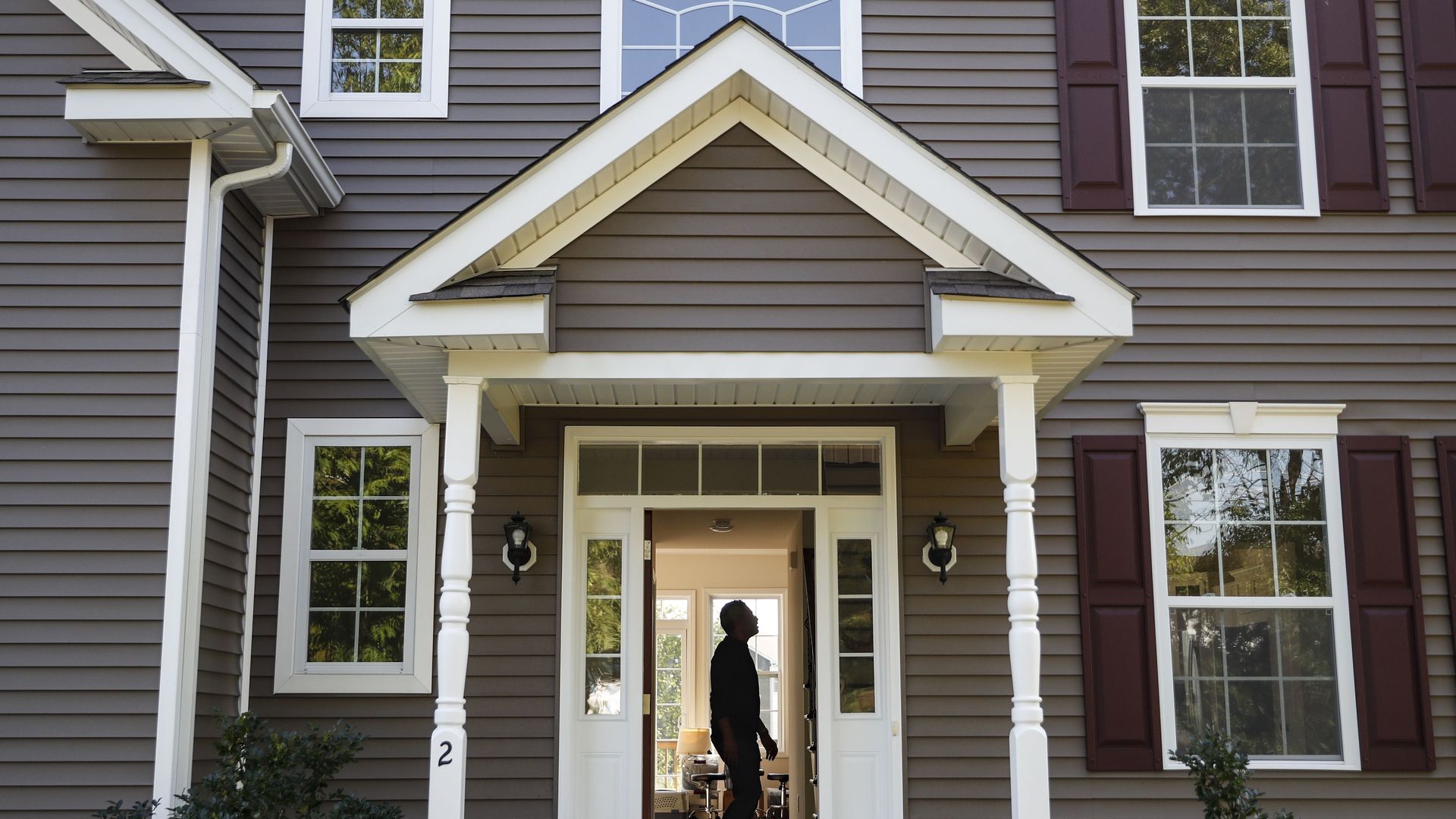 A man stands in the doorway to his house