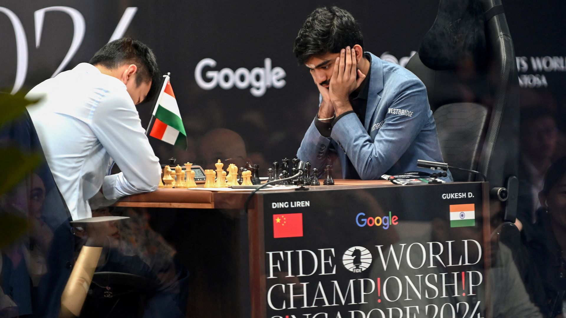 China's chess grandmaster Ding Liren (L) and India's grandmaster Gukesh Dommaraju (R) compete in game 14 of the 2024 FIDE World Championship in Singapore on December 12, 2024. 
