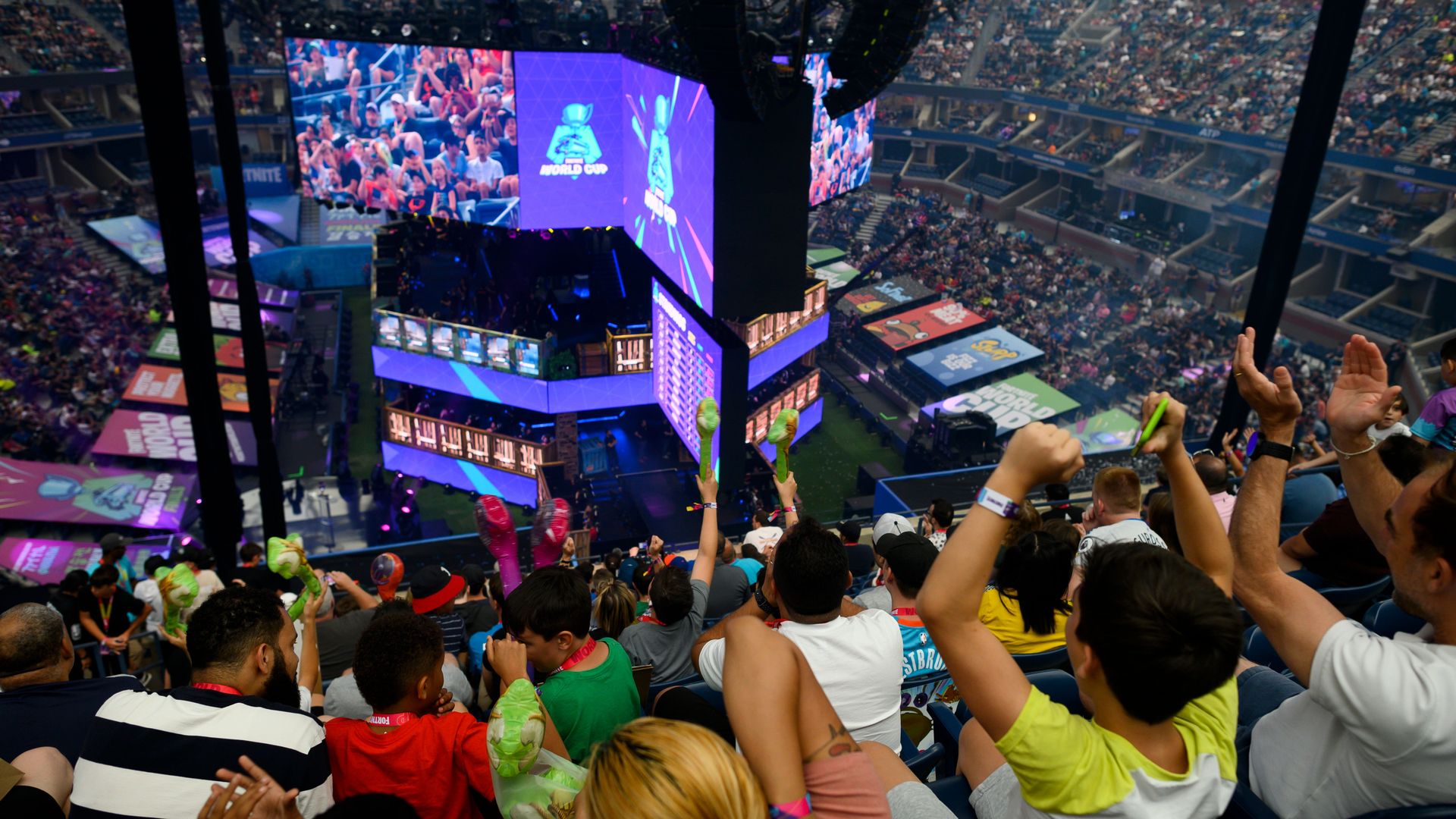 Fans celebrate while watching a video game tournament on a jumbotron. 