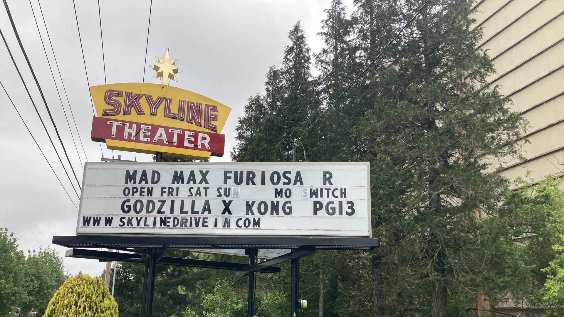 A neon sign advertises the featured movies outside a drive-in theater. 