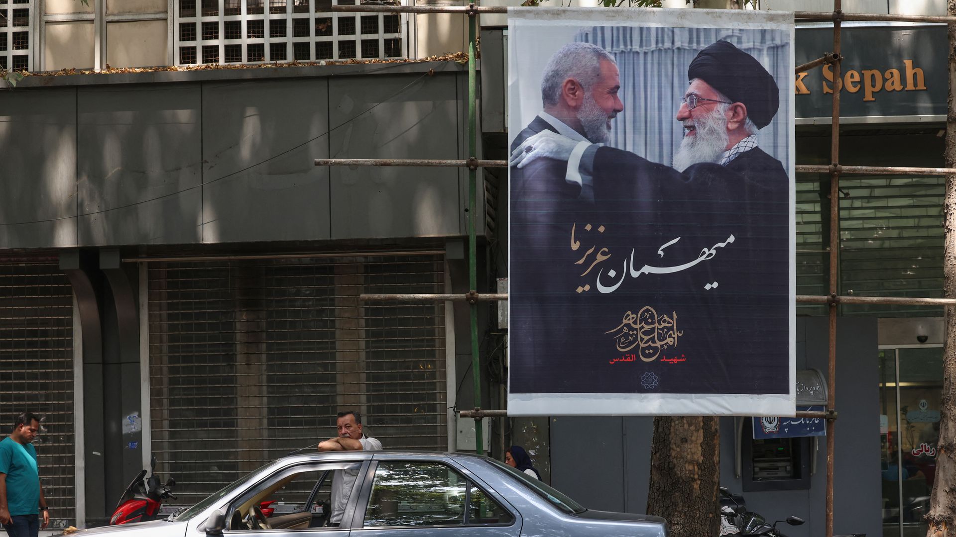 People walk past a poster of Iranian supreme leader Ayatollah Ali Khamenei (R) and slain Palestinian Hamas leader Ismail Haniyeh in Iran's capital Tehran on August 10, 2024