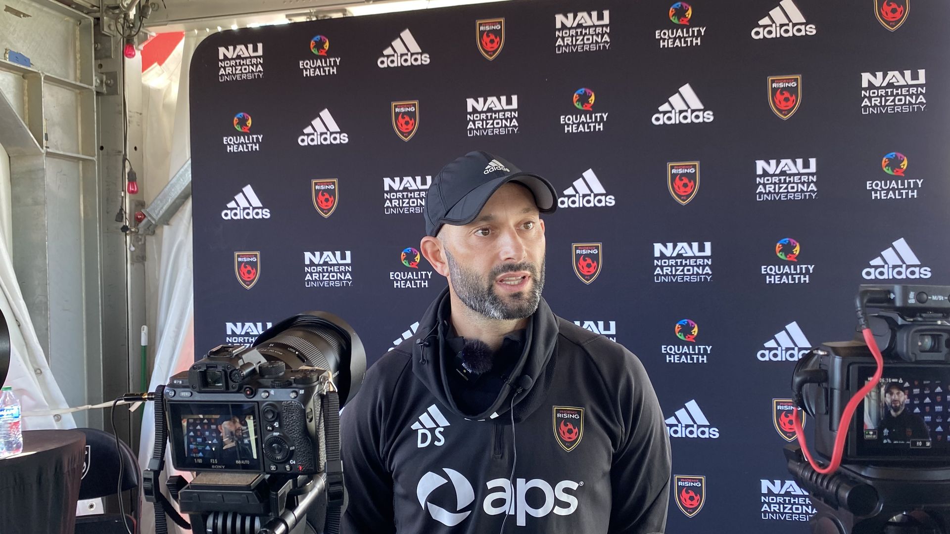 A man speaks in front of television cameras.