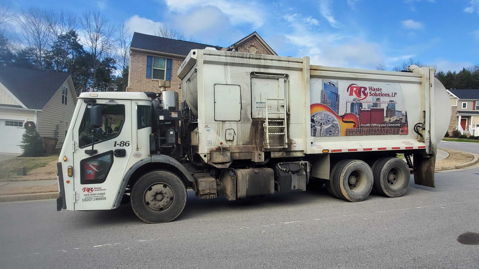 A trash truck driving through a residential neighborhood.