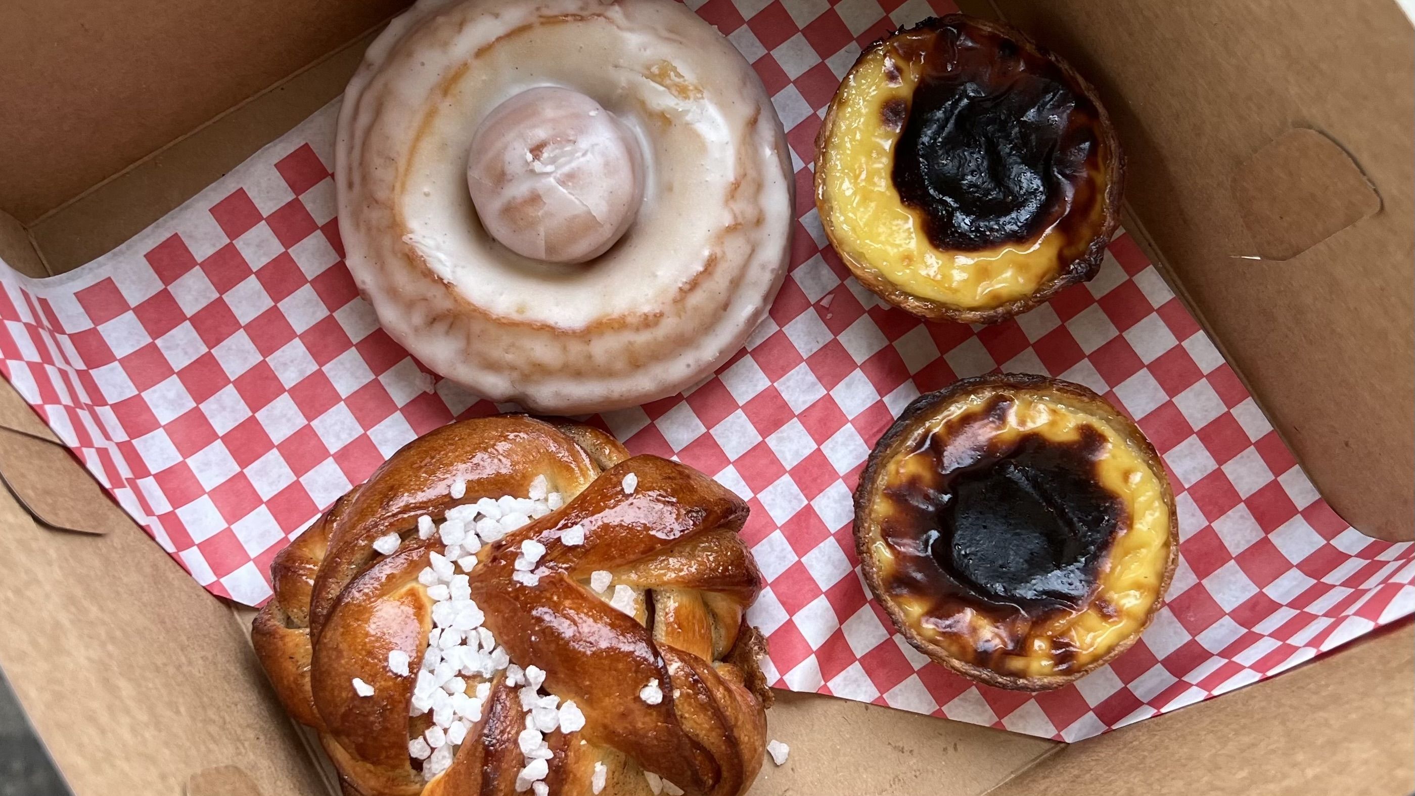 A pastry box filled with goods on a red gingham paper.