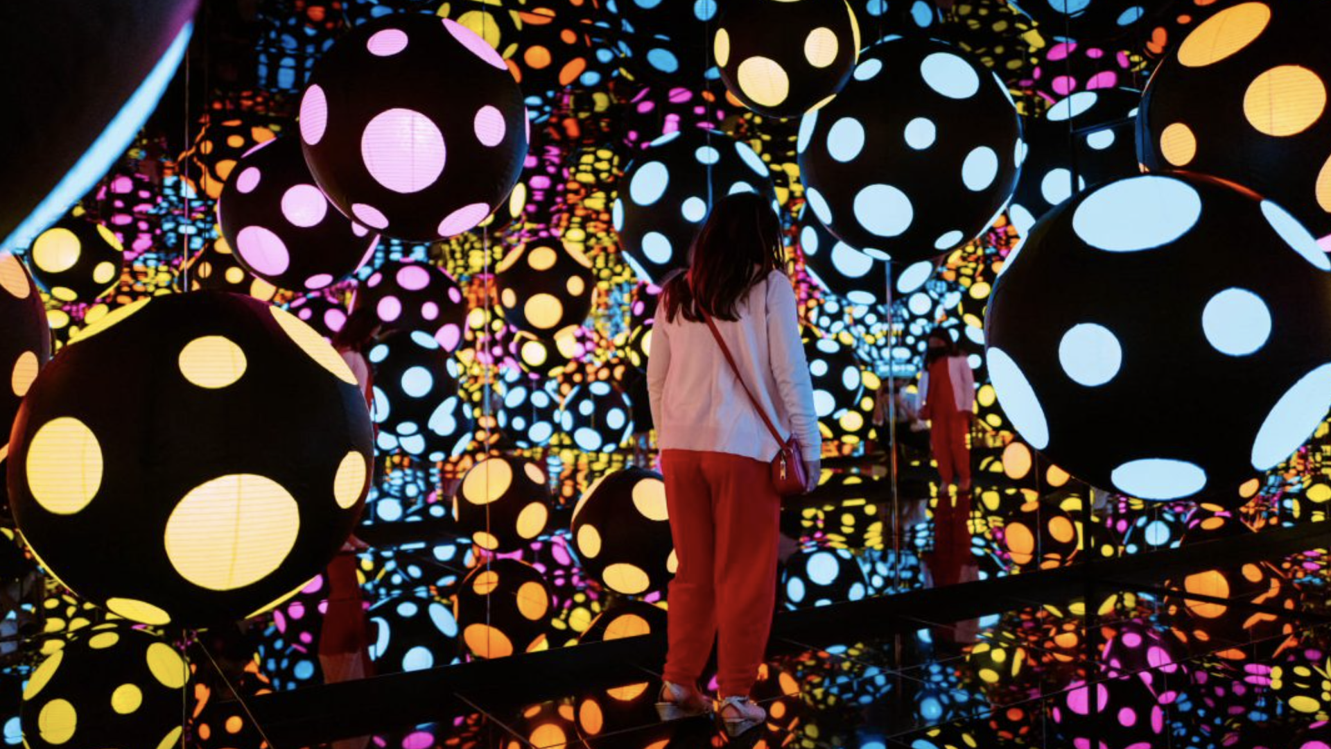 A visitor enjoy's one of the Kusama exhibition infinity mirror rooms.
