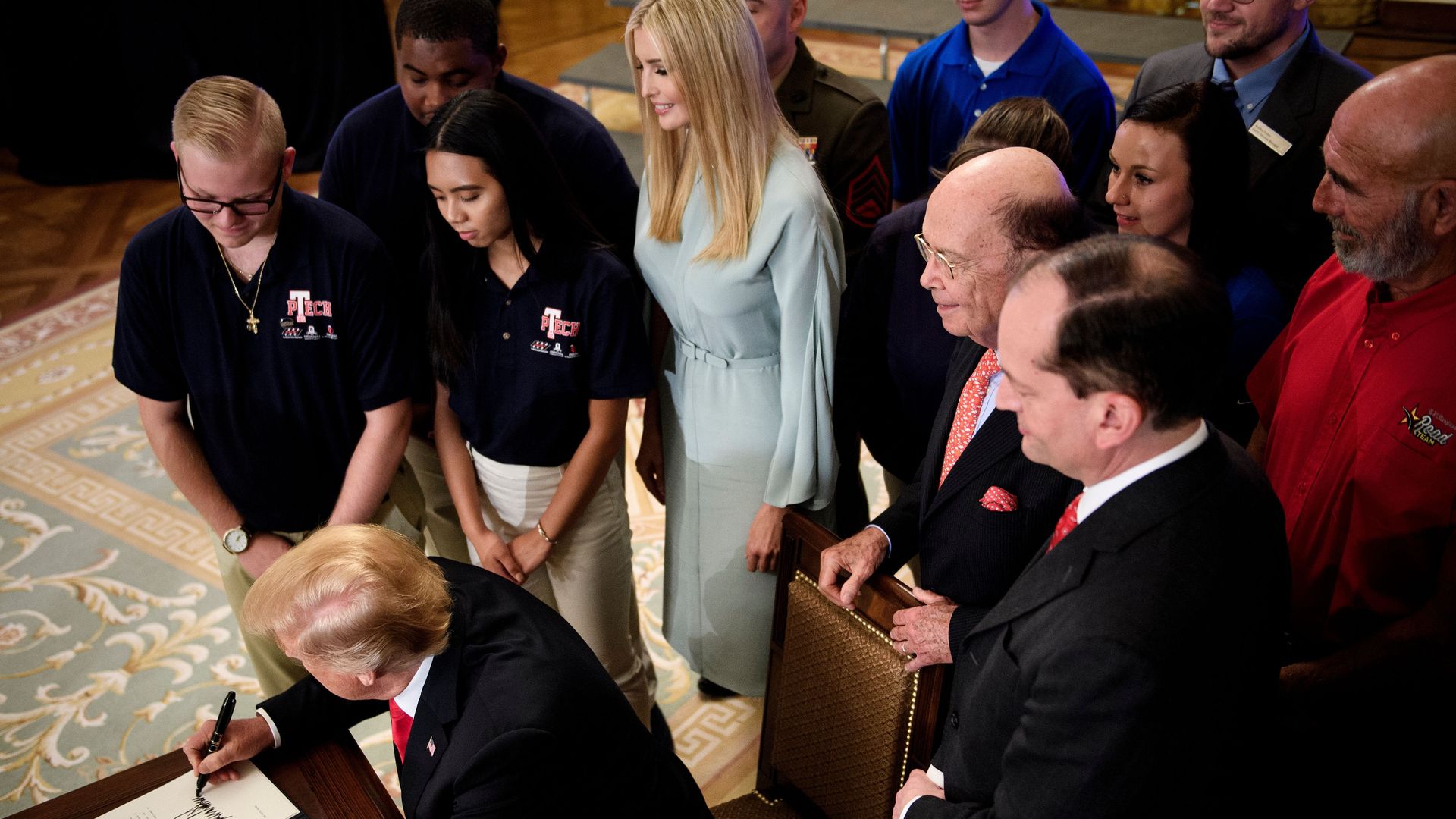 Donald Trump surrounded by Ivanka Trump and guests signing executive order on worker training