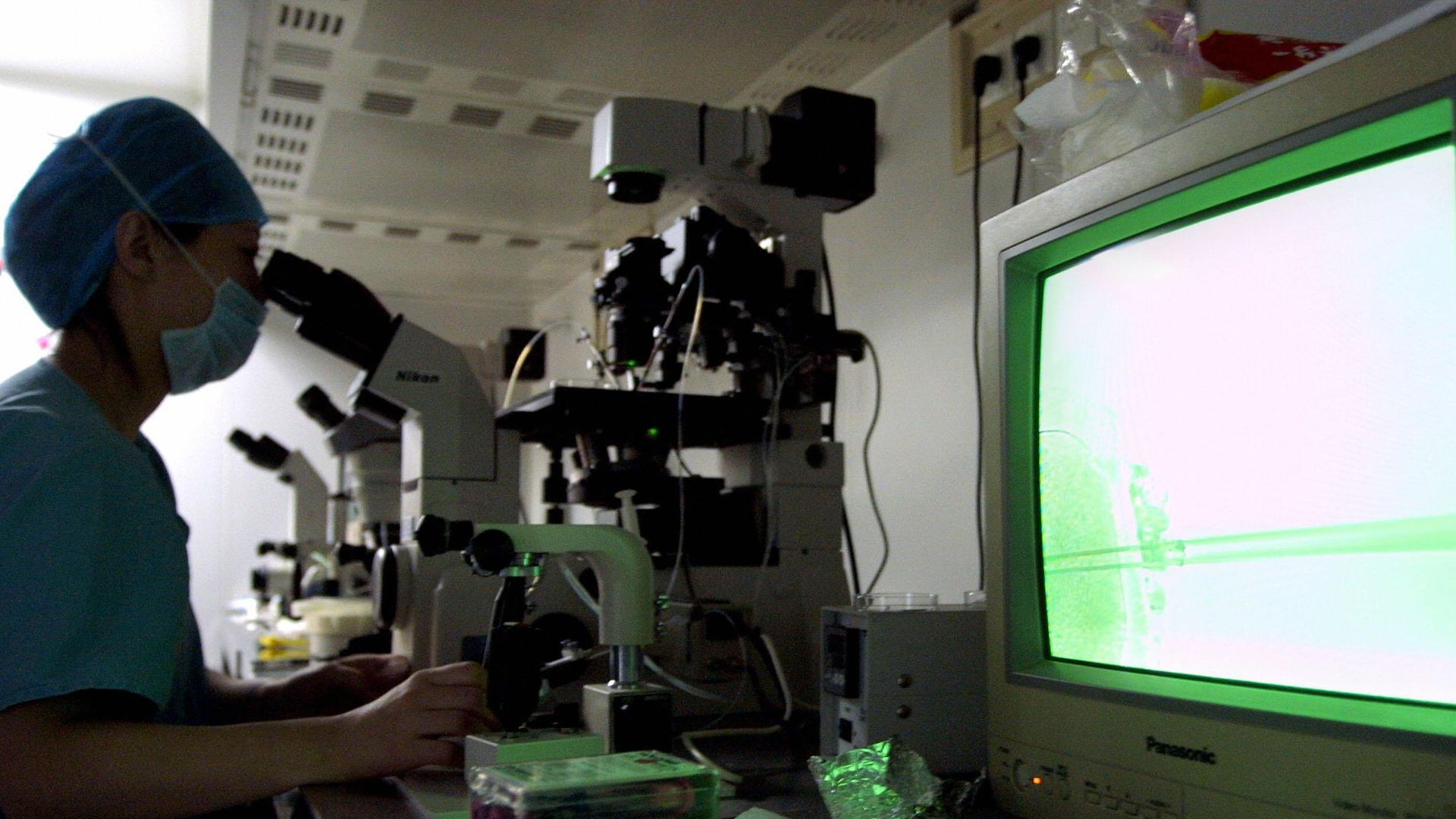 Doctor at Peking University's fertility clinic looking through microscope