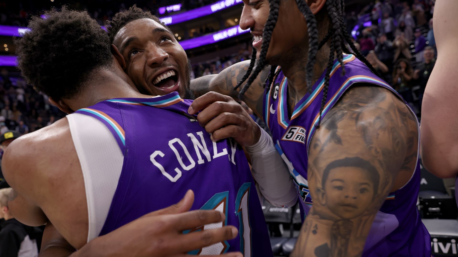 Two basketball players hug another basketball player.