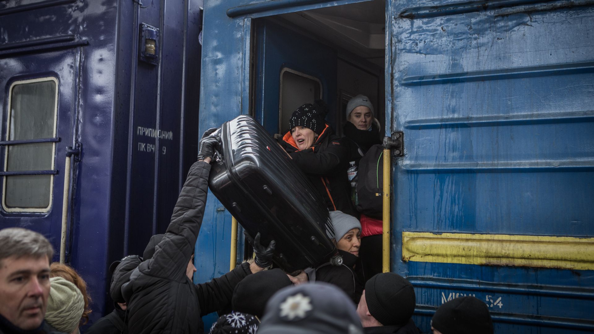Photo of people loading luggage on to a blue departing train