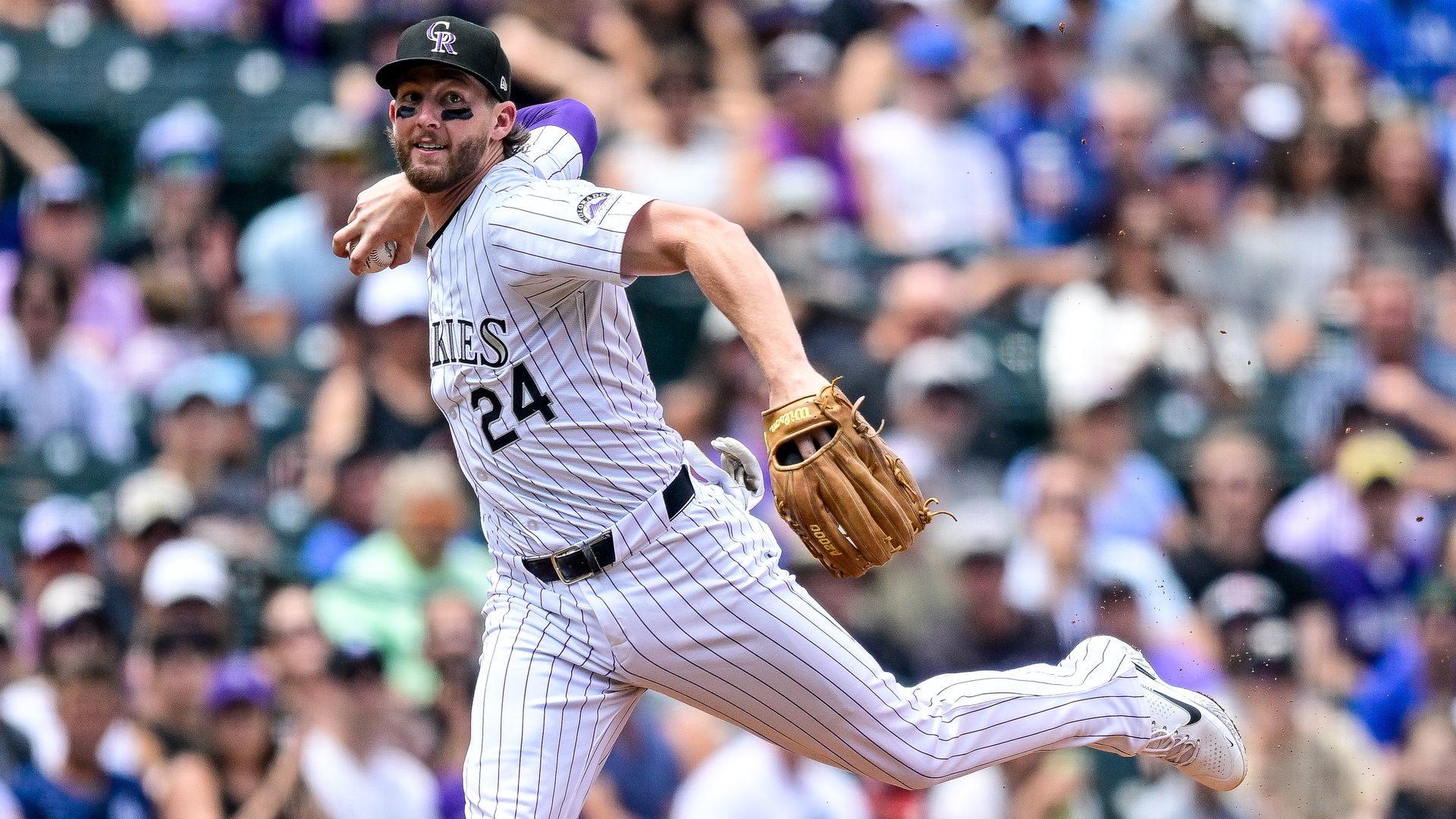 A man in pinstripe shirt and pants raises his arm to throw a baseball during a game.  