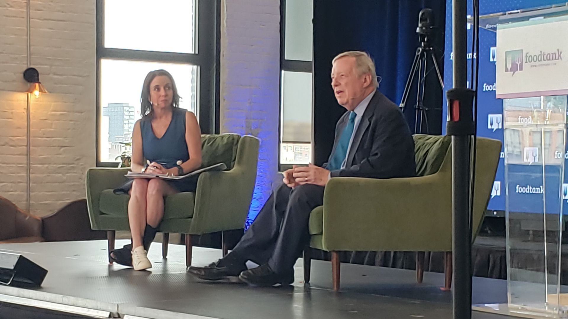Photo of two people sitting on a stage talking to audience.