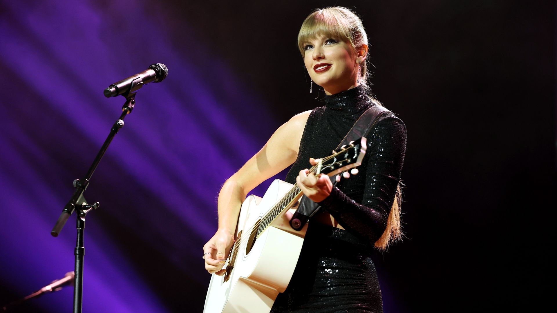A photo of a woman on stage with a guitar.