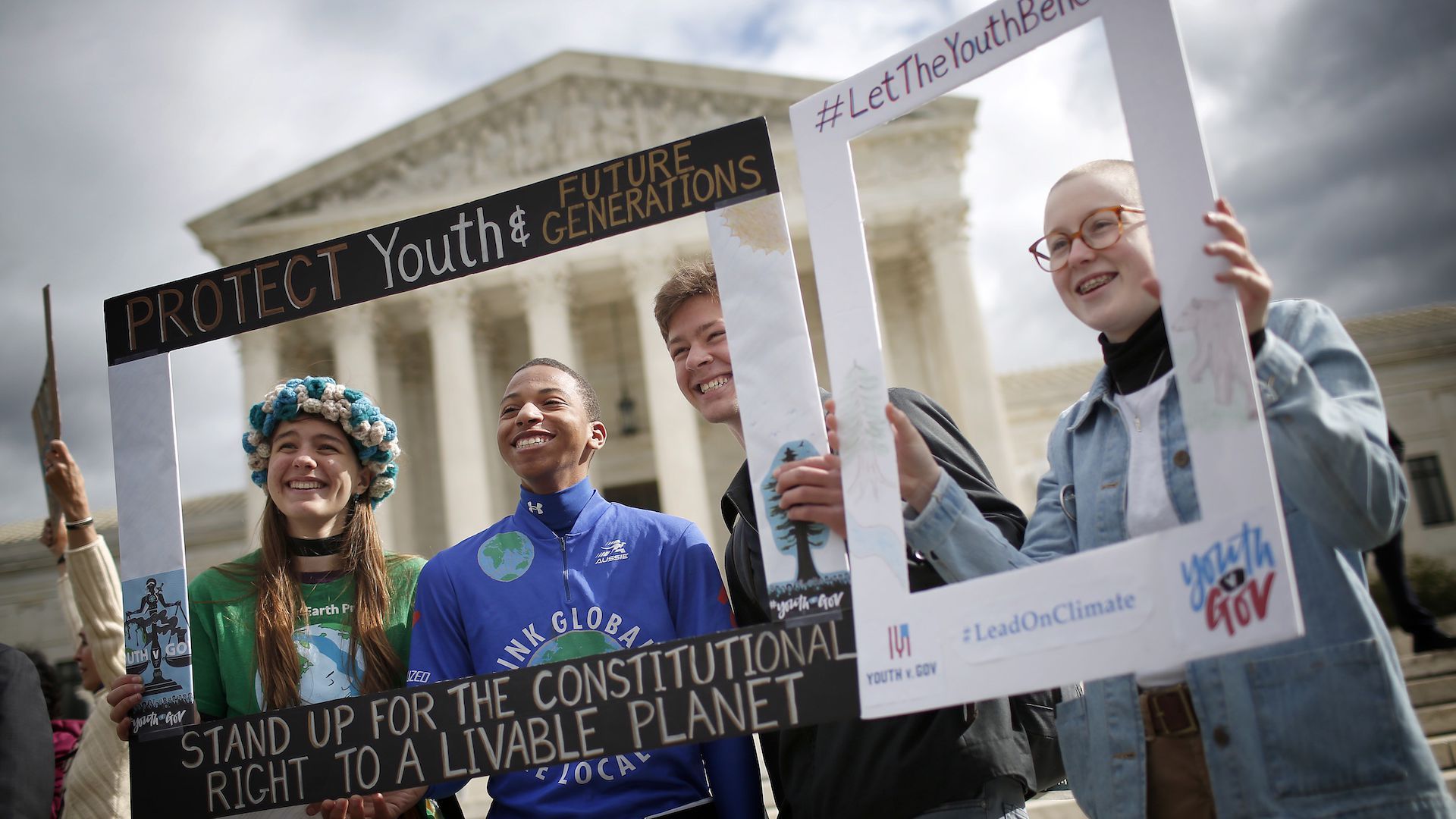 Photo of some of the 21 youth standing in front of the Supreme Court holding protest frames around their faces