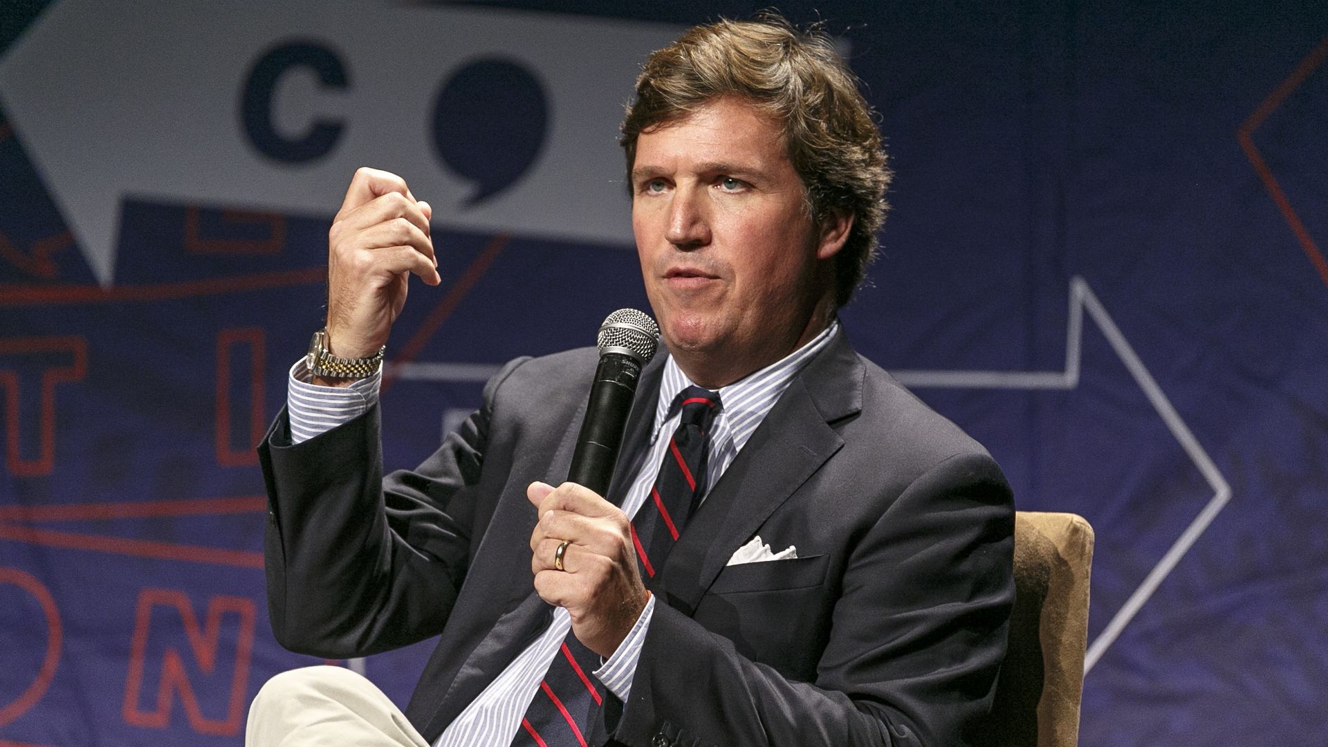Tucker Carlson gestures while speaking at a conference