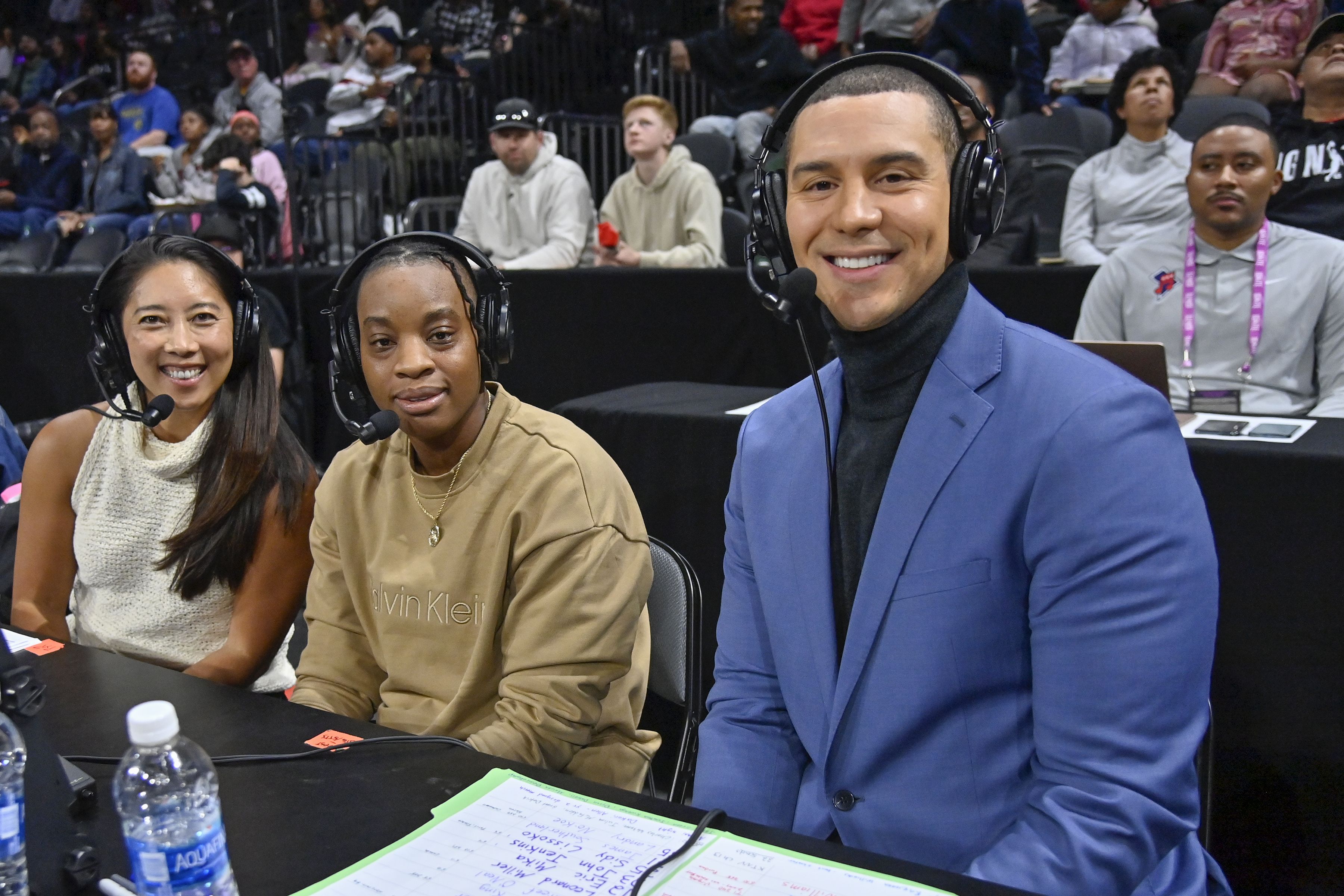 Photo of broadcasters smiling for camera on side of court 