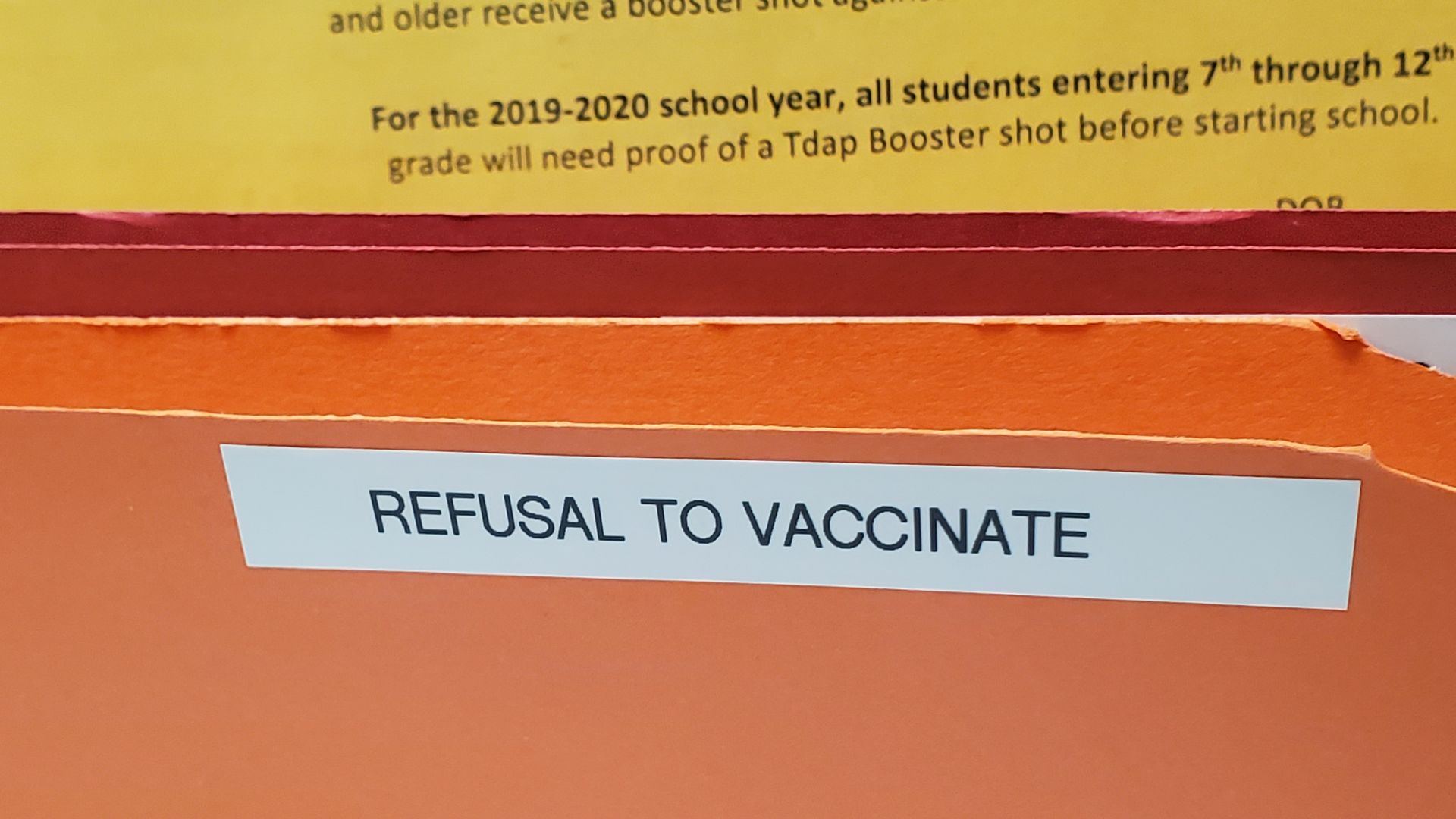 Close-up of folder containing medical forms and labeled Refusal to Vaccinate
