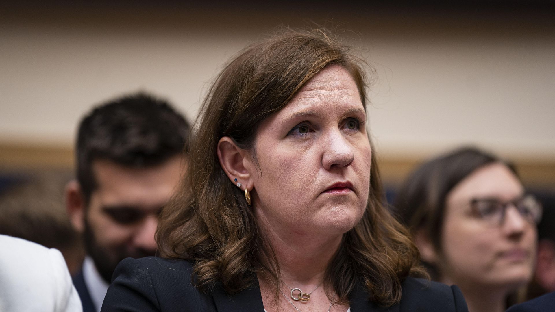Rebecca Slaughter, the fired Federal Trade Commission commissioner, wearing brown, shoulder-length hair, a navy jacket, white blouse and two necklaces, looks up during a Senate hearing.