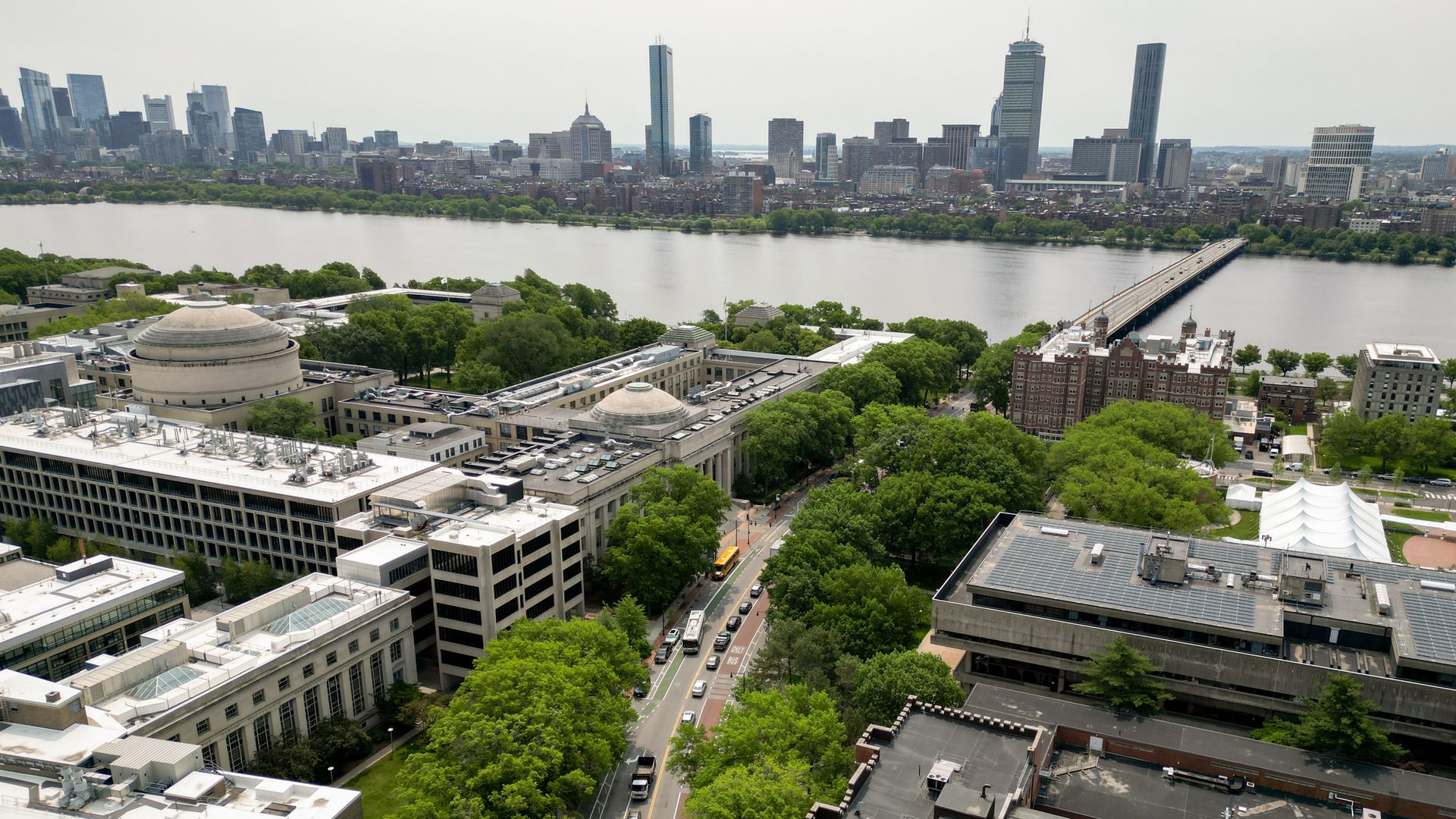 An aerial view of a college campus in Cambridge, with the charles River and Boston's Back Bay neighborhood visible in the distance. 