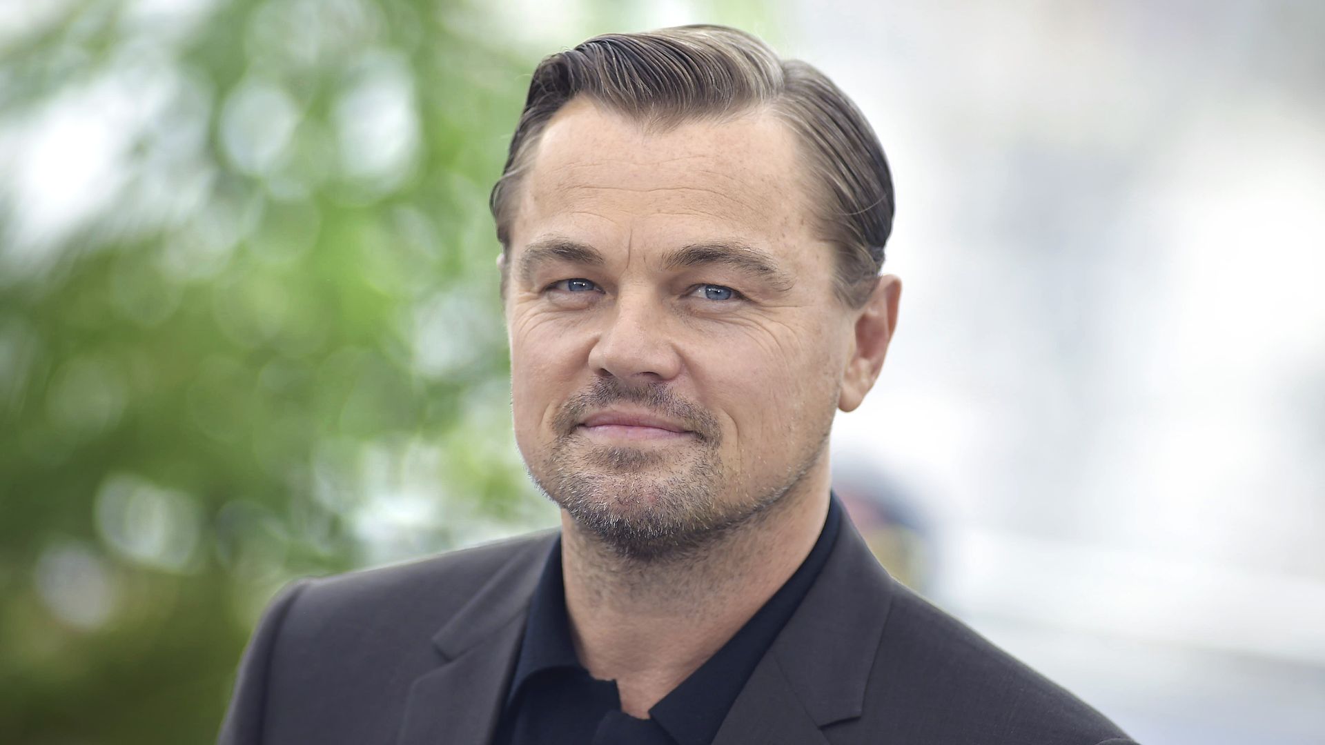 Leonardo Di Caprio in a black shirt and gray jacket.