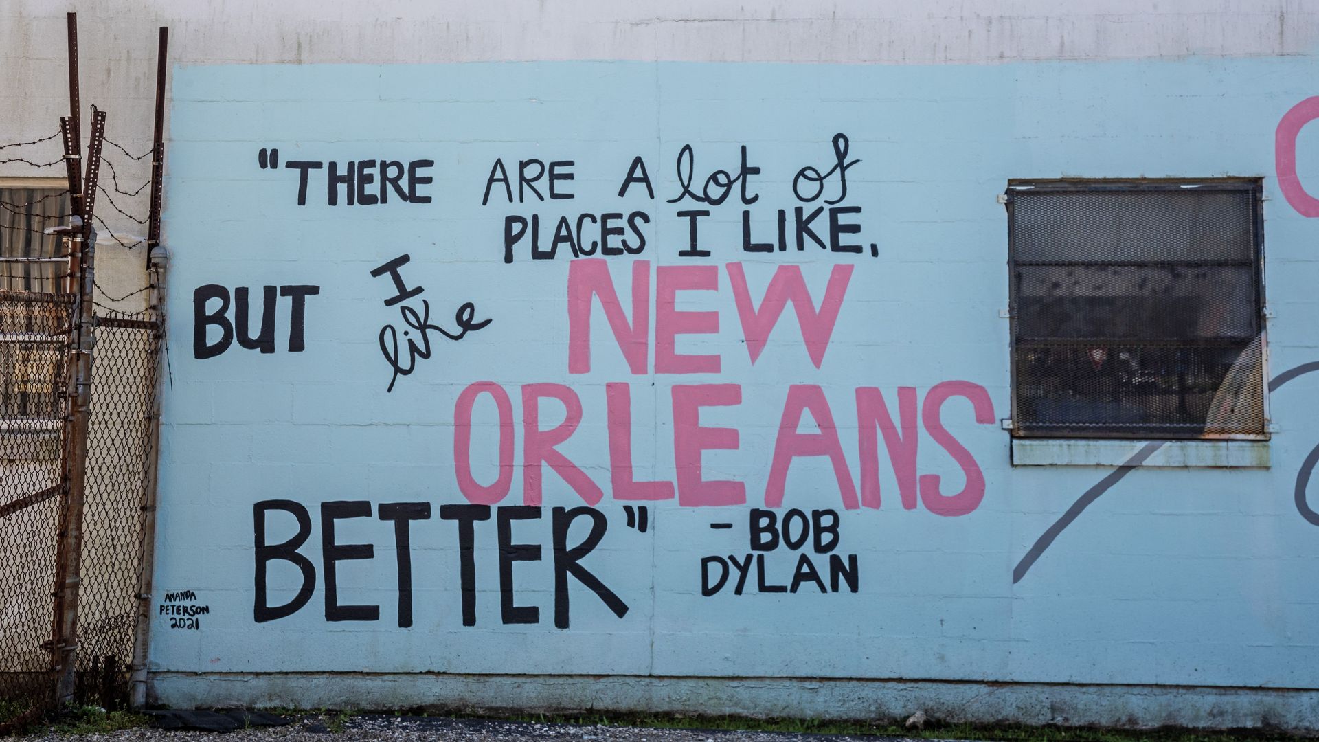Image shows a mural that says "There are a lot of places I like, but I like New Orleans better" by Bob Dylan.