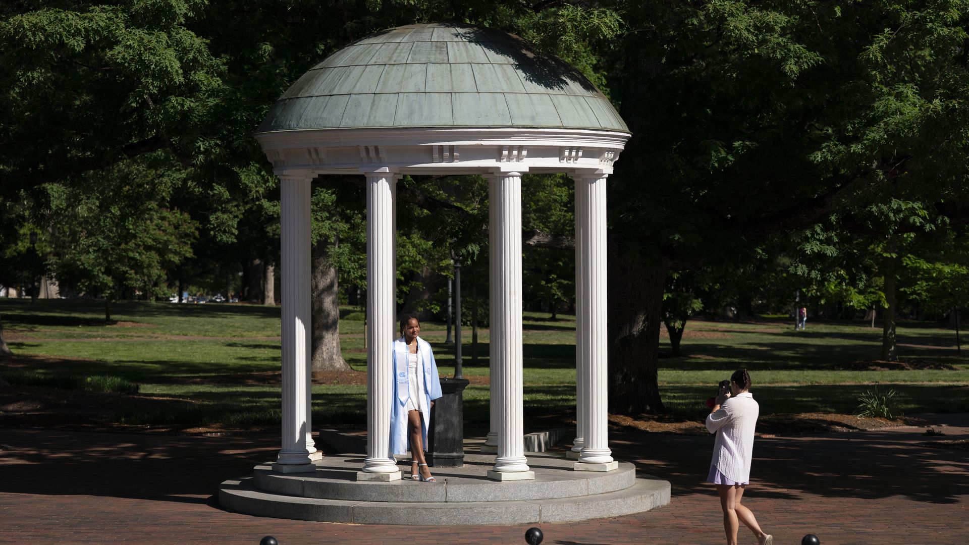CHAPEL HILL, NORTH CAROLINA - MAY 1: A soon to be college graduate poses for photos at the Old Well at the University of North Carolina on May 1, 2024 in Chapel Hill, North Carolina. The University of North Carolina was the first public university to accept and graduate students in the United States