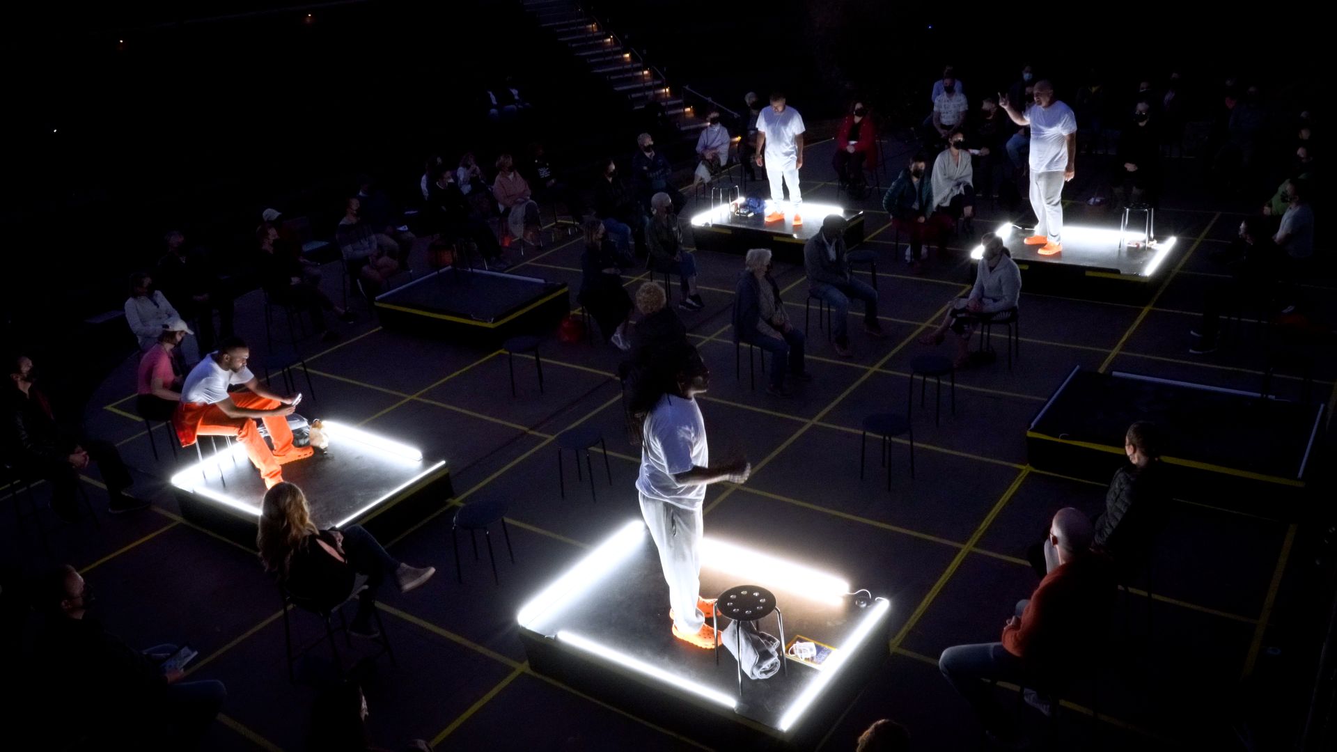 Four actors stand in lit-up squares during a performance of the play "The Box" in San Rafael, California, in 2021.