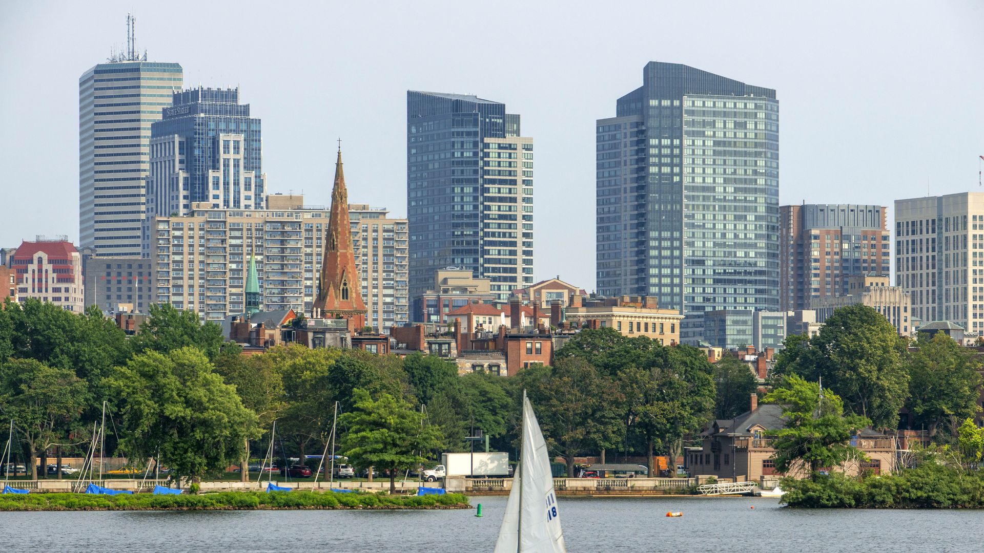 Sail boat in Boston Harbor, Boston against the cityscape of Back Bay Boston, Massachusetts, USA from across the Charles River.