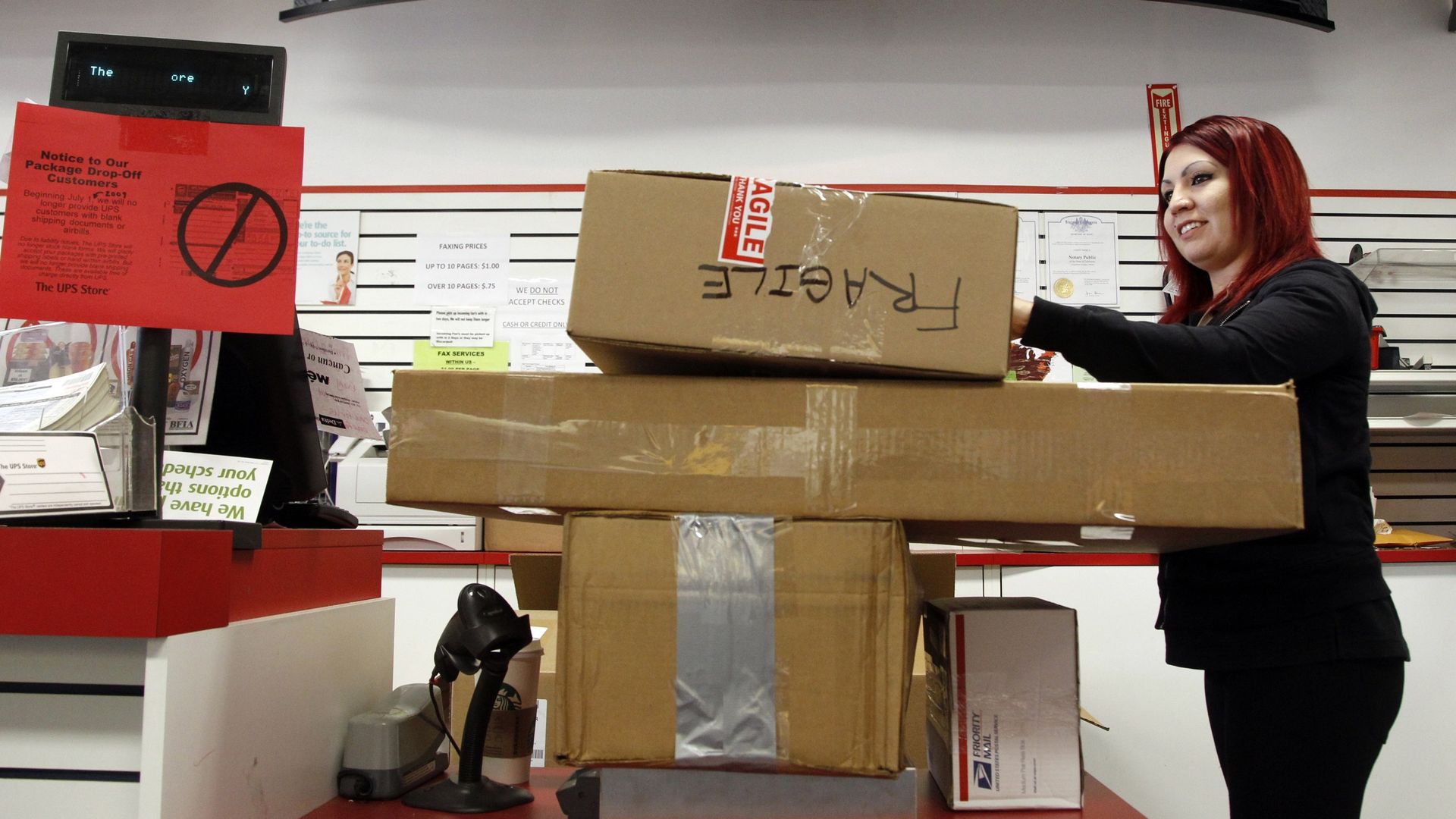 Woman with red hair stacks three UPS packages.