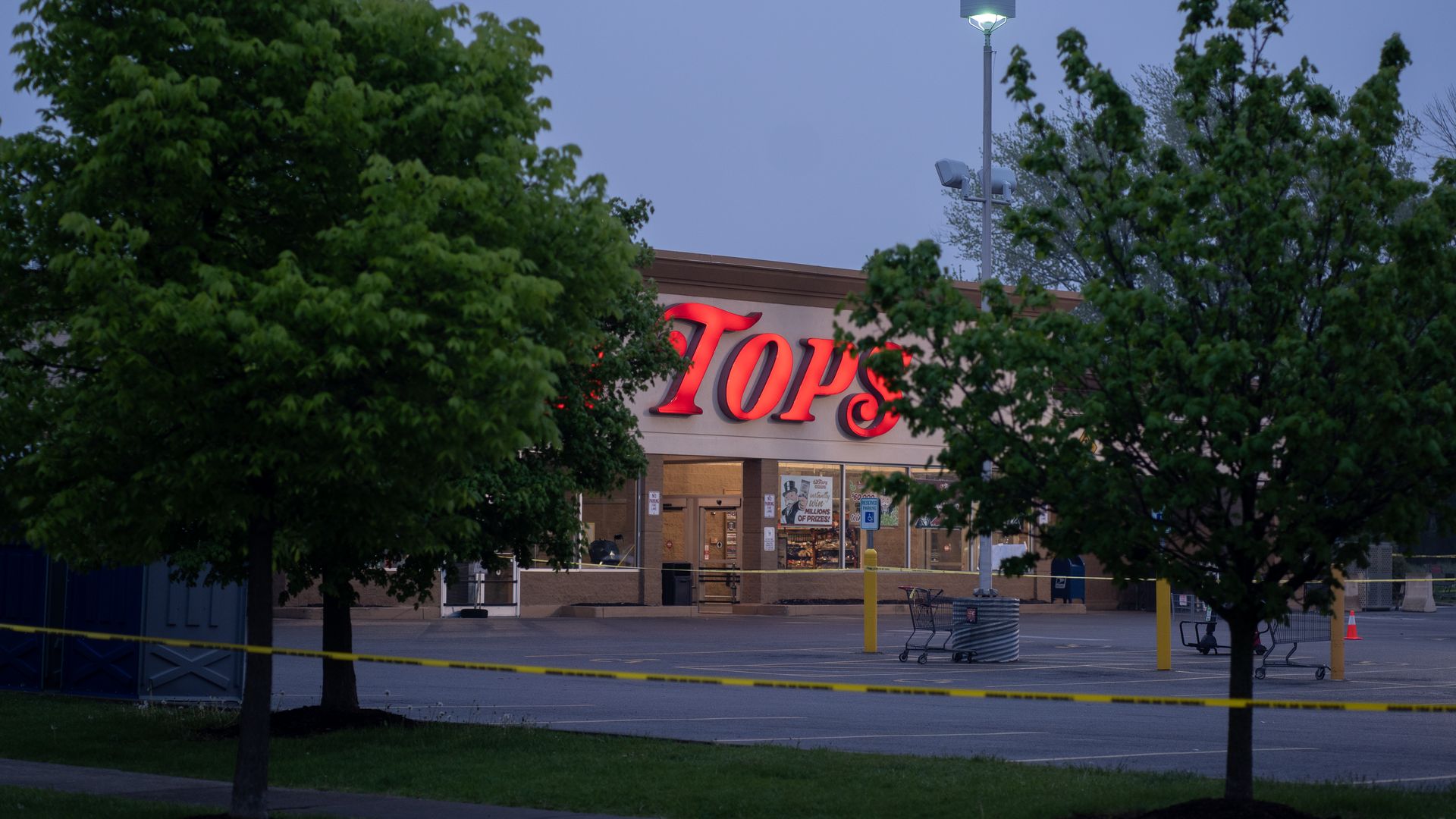 Photo of the entrance to a Tops grocery store, with two trees on either side of the store's logo